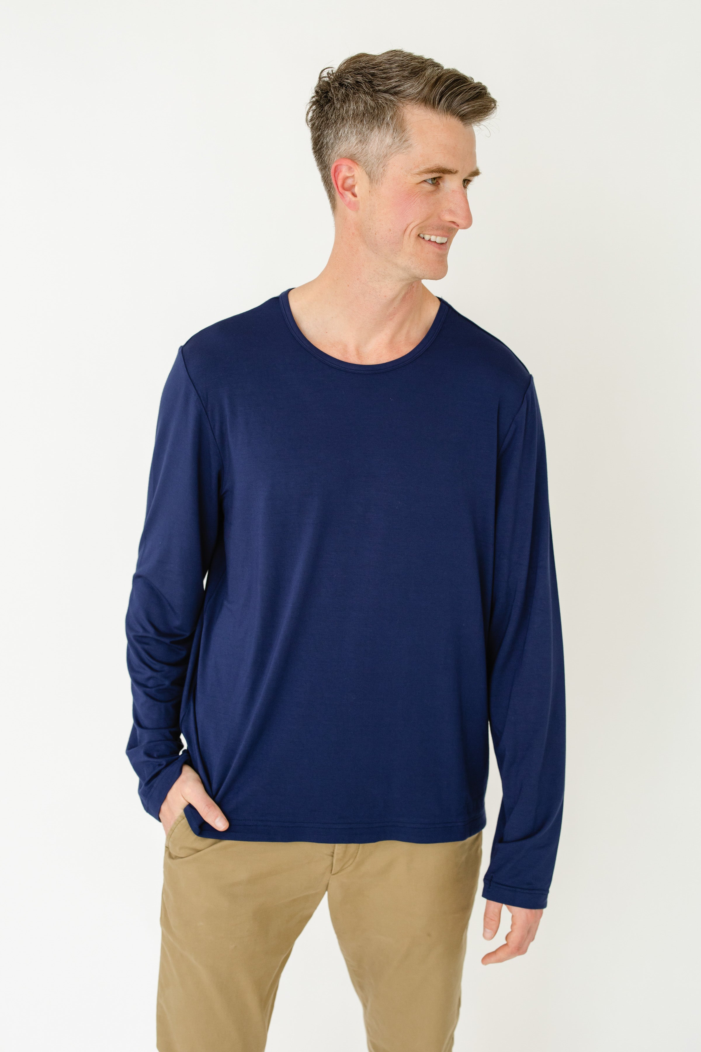 Man wearing a navy long-sleeve shirt and beige pants on a white background