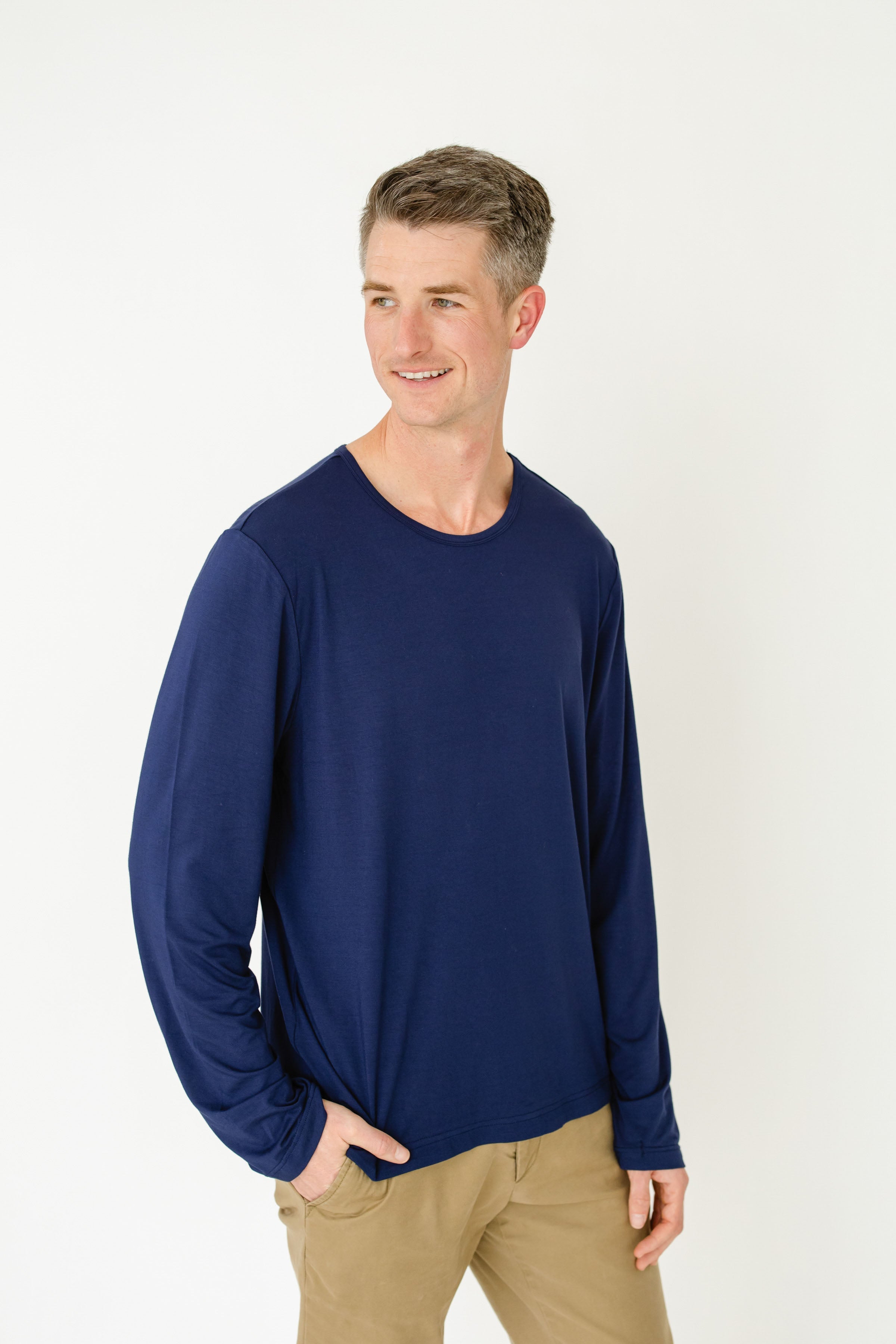 Man wearing a blue long-sleeve shirt and beige pants on a white background