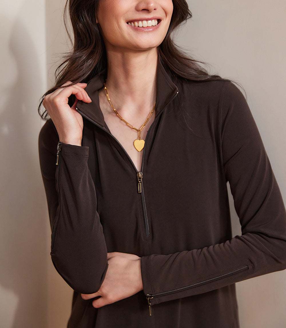 Woman wearing a brown zip-up top with a plain background