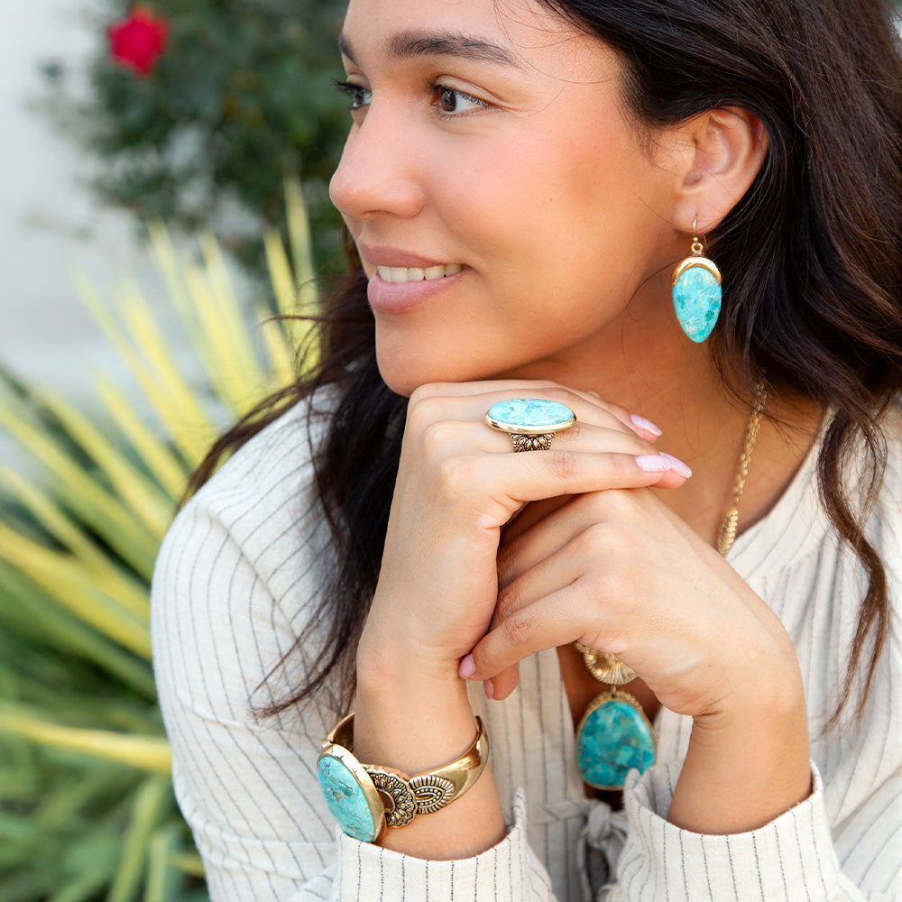 Woman wearing turquoise jewelry with a blurred outdoor background
