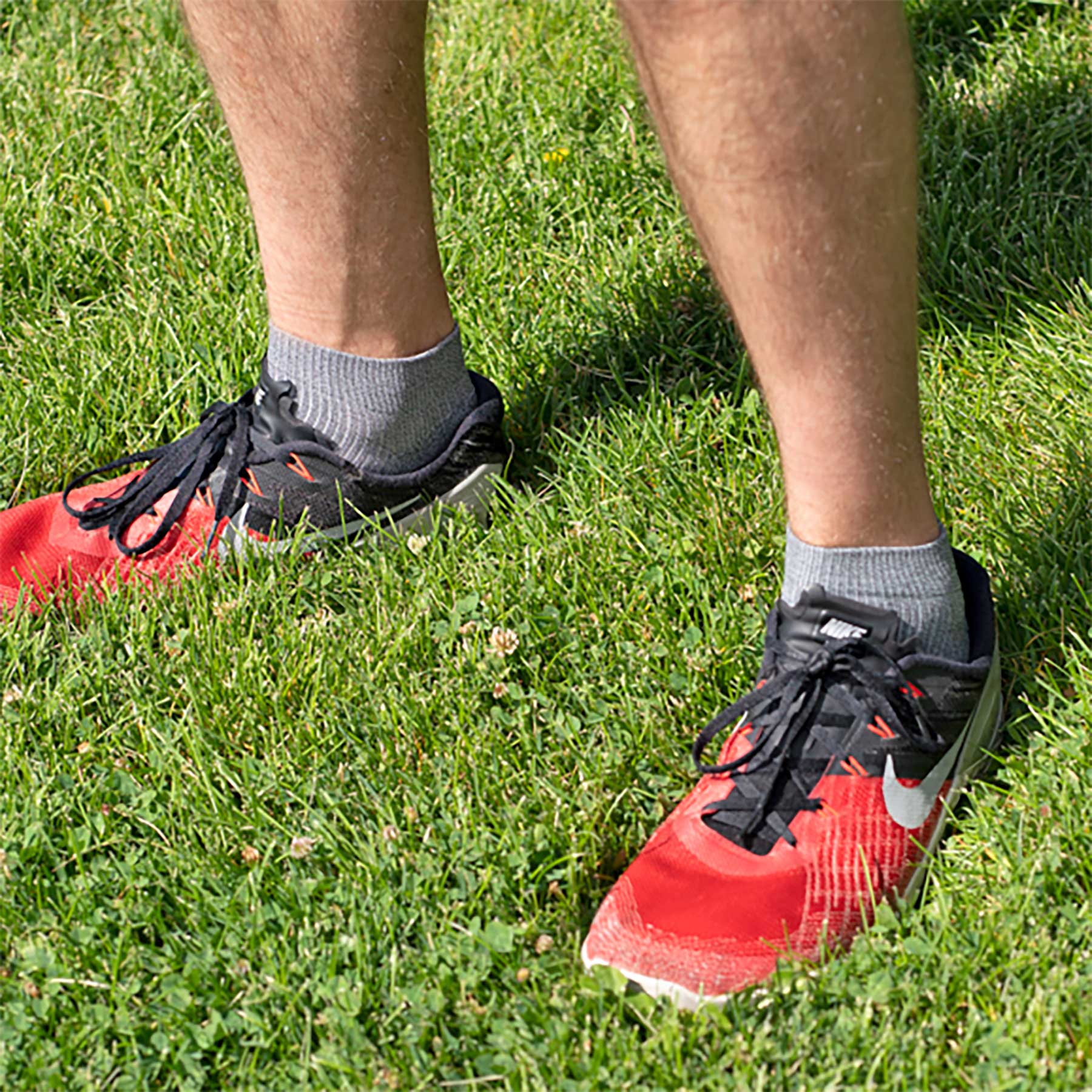 Red running shoes with black laces on grass