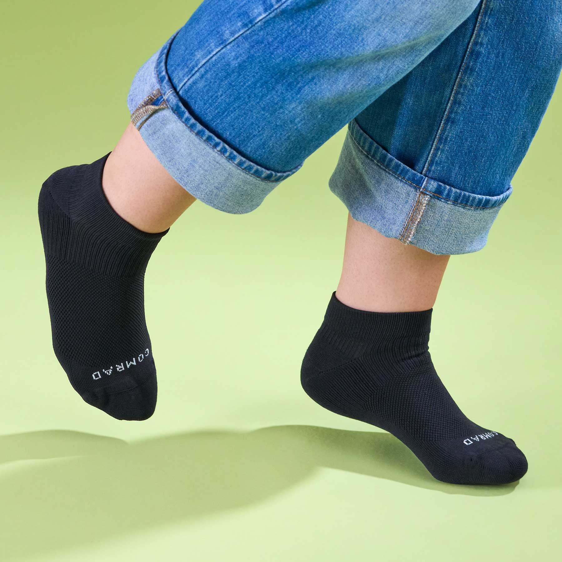 Person wearing black socks with visible branding on a light green background