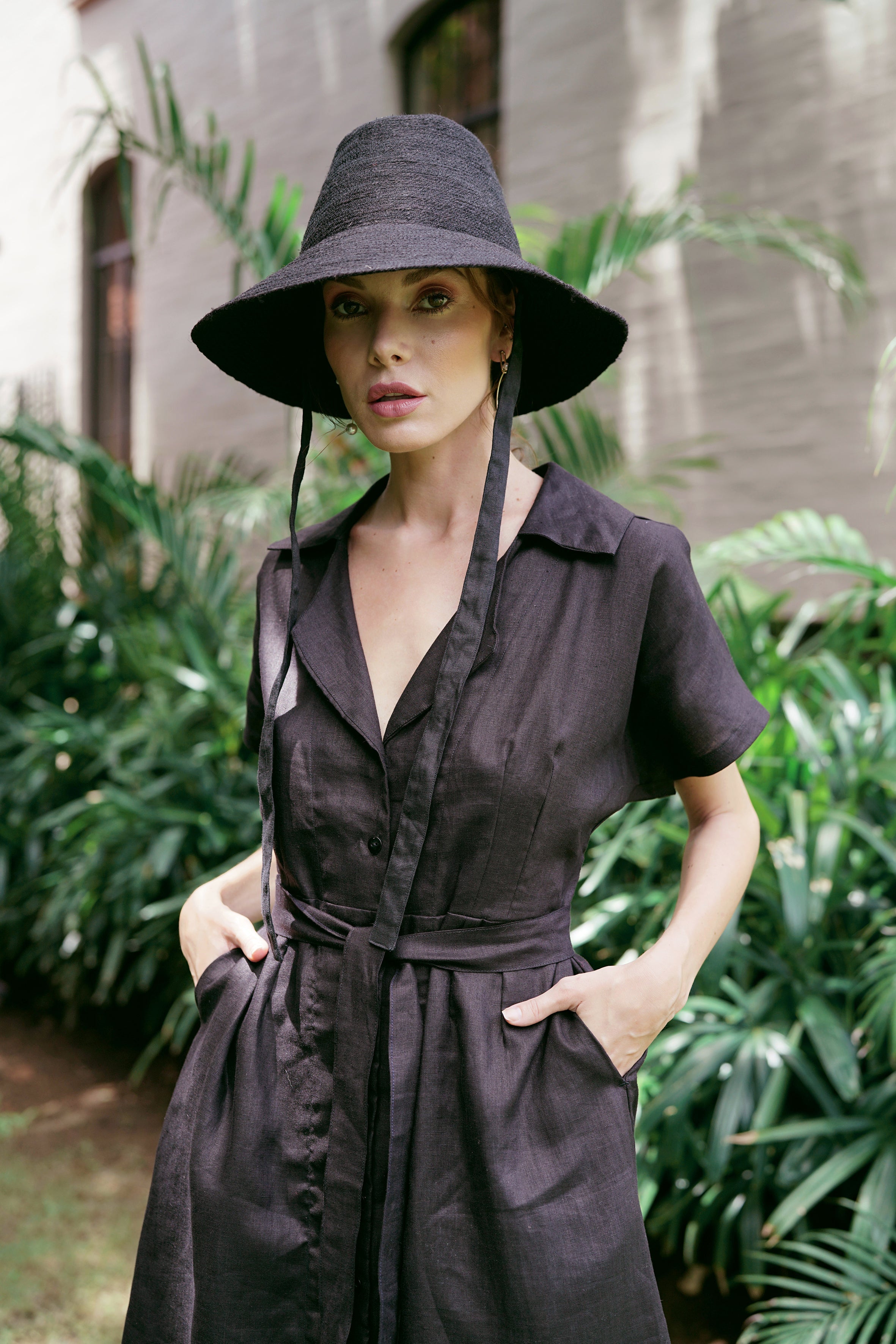 Woman wearing a black outfit with a wide-brimmed hat in an outdoor setting
