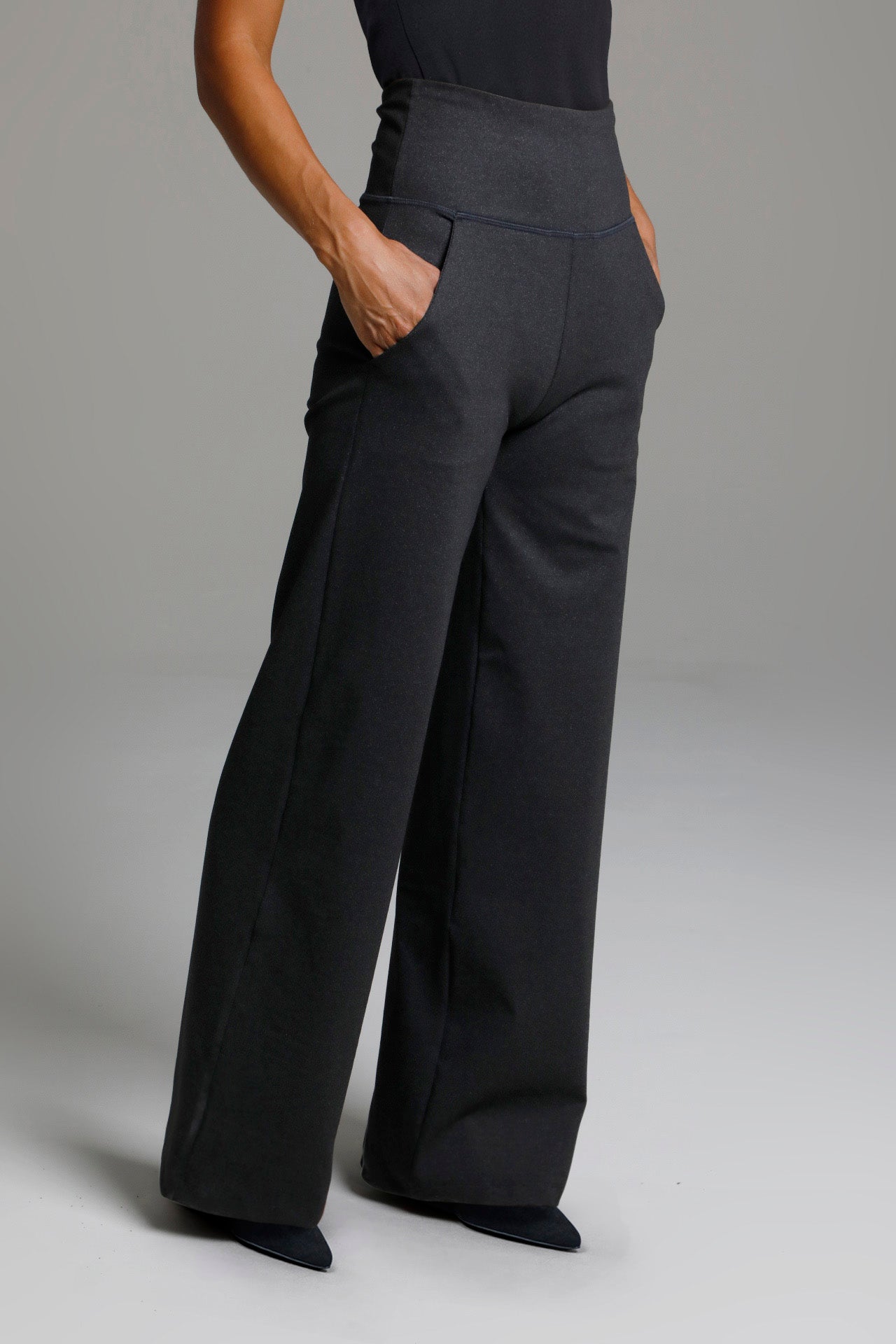 Person wearing black high-waisted pants on a plain background