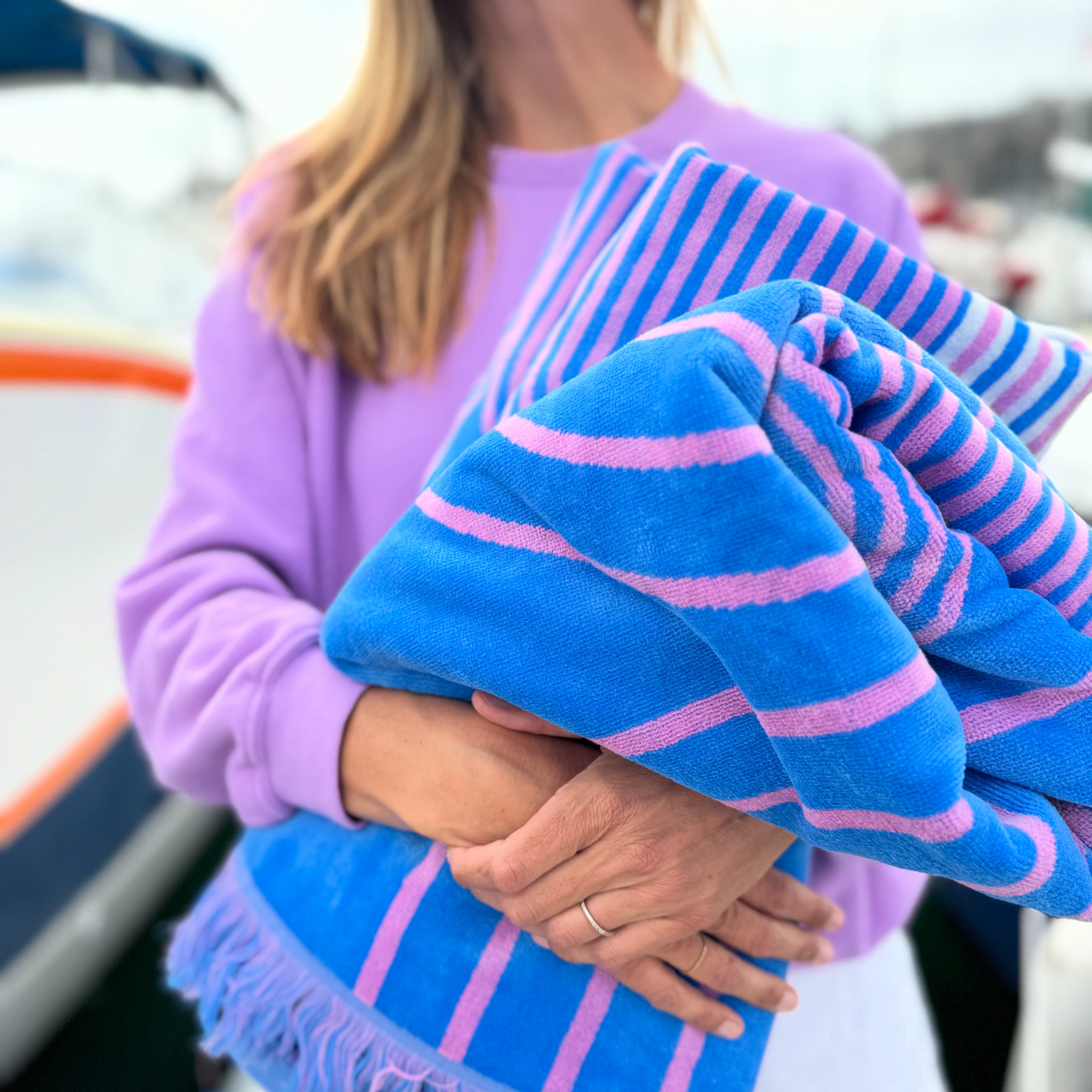 Person holding a blue and pink striped towel with a blurred background