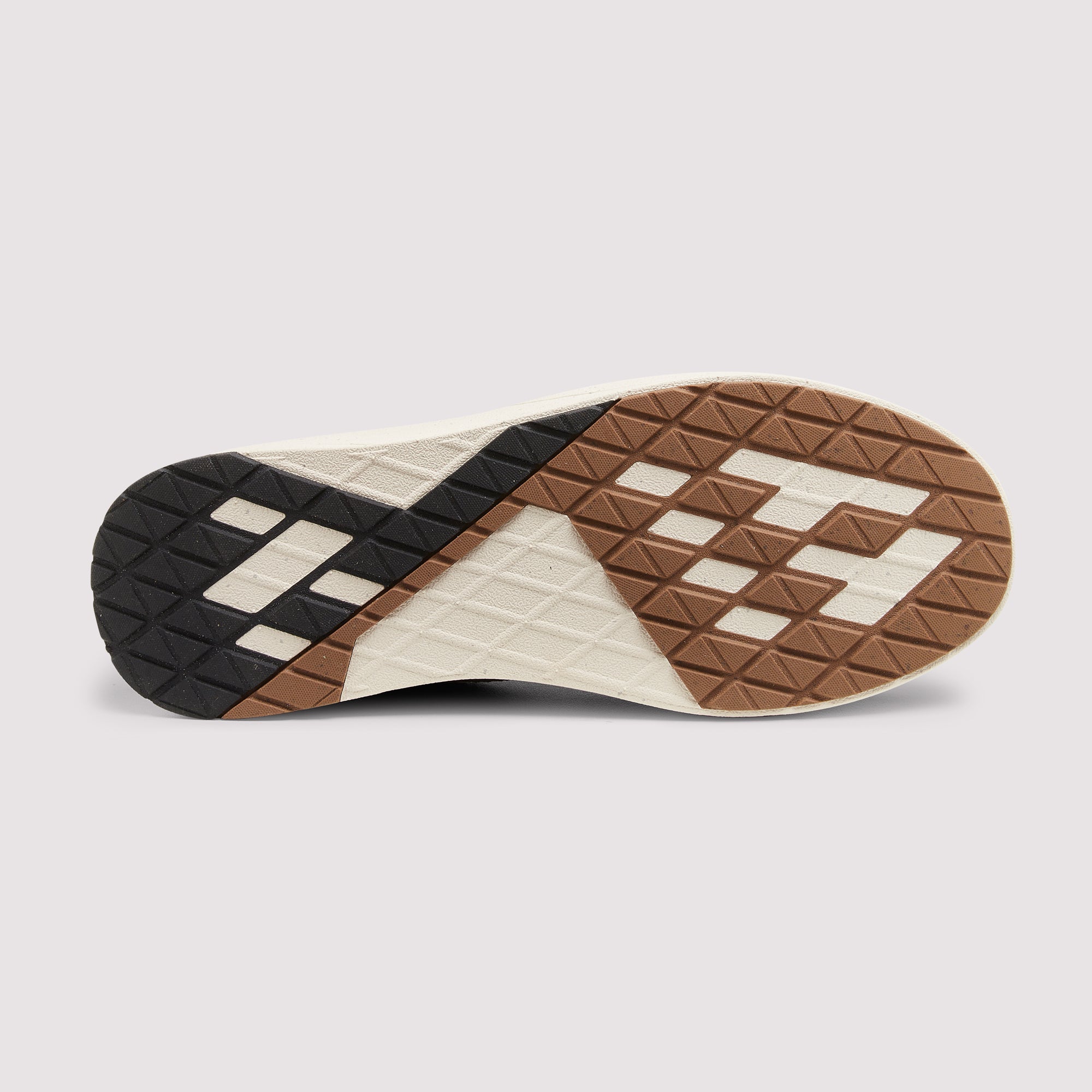 The outsole of a sneaker shown from a top-down view, featuring a geometric pattern in black, brown, and off-white rubber.