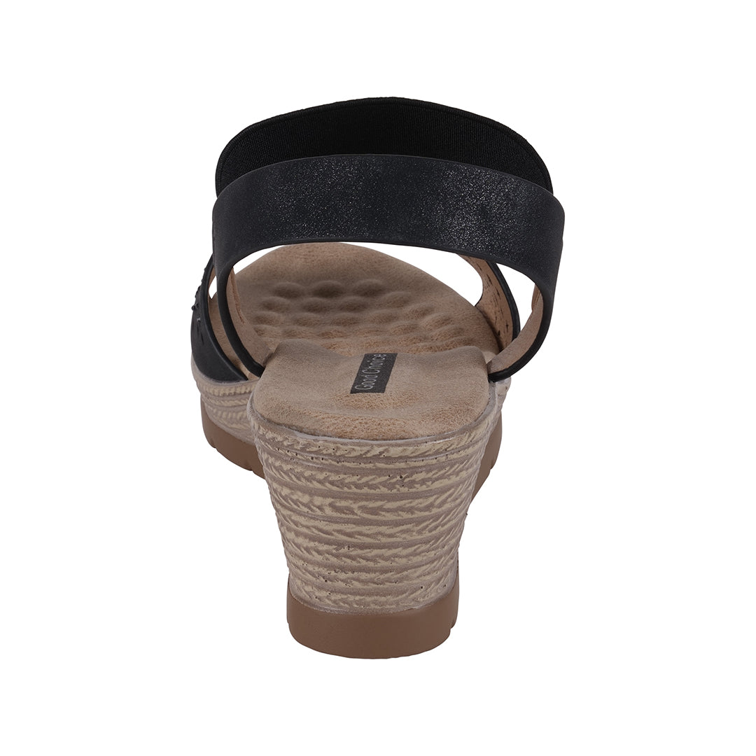Wedge sandal with black strap and textured sole on a white background