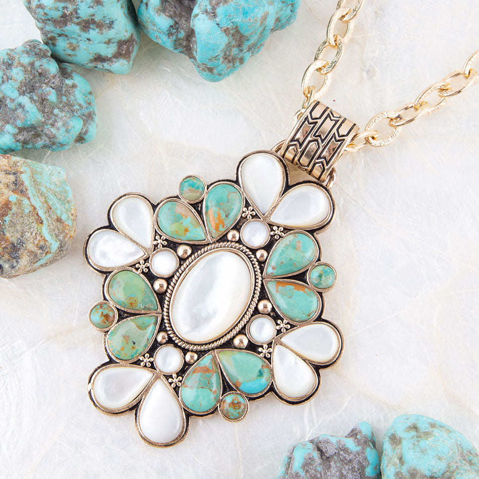Necklace with turquoise and white stone pendant on a textured surface