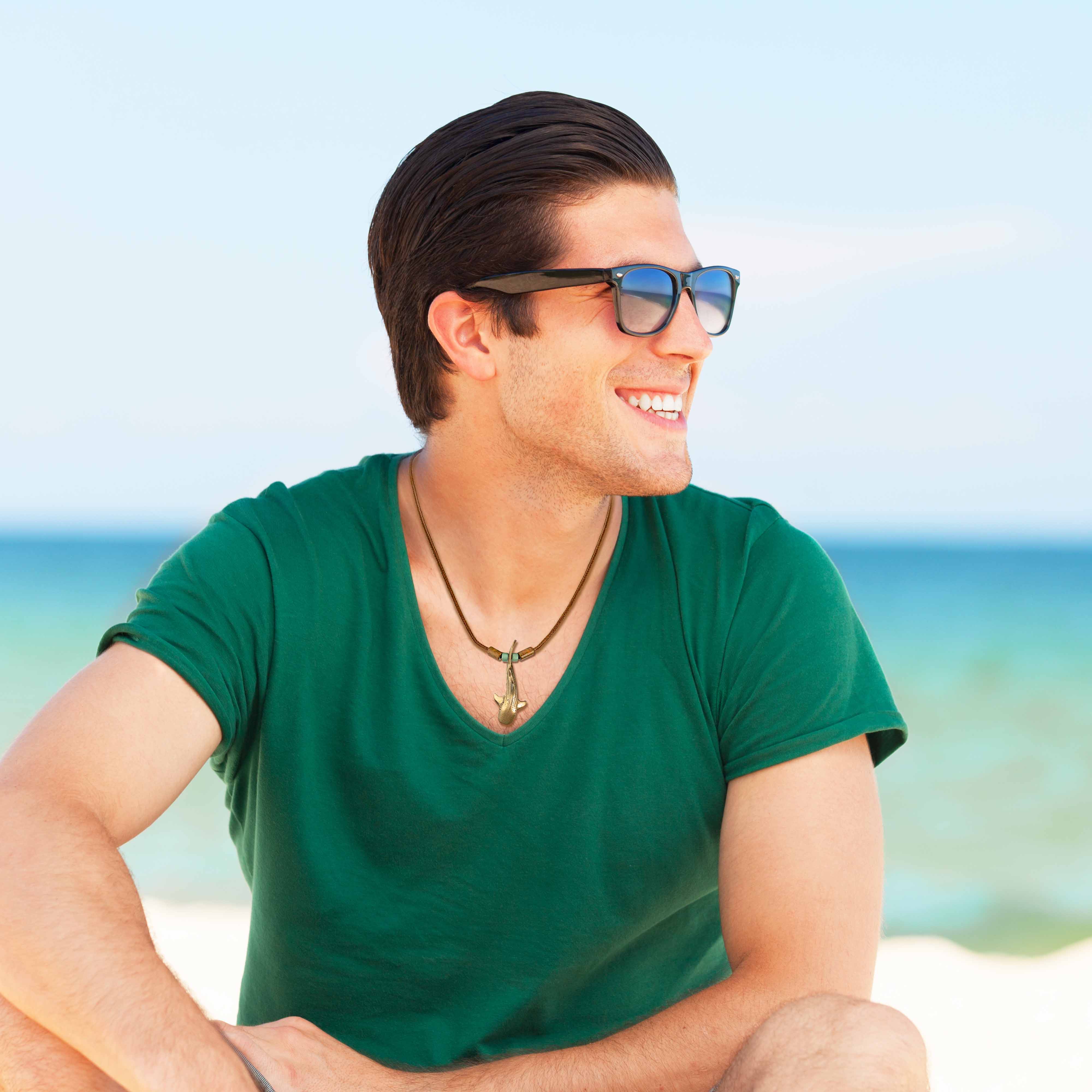 Man wearing sunglasses and a green shirt on a beach