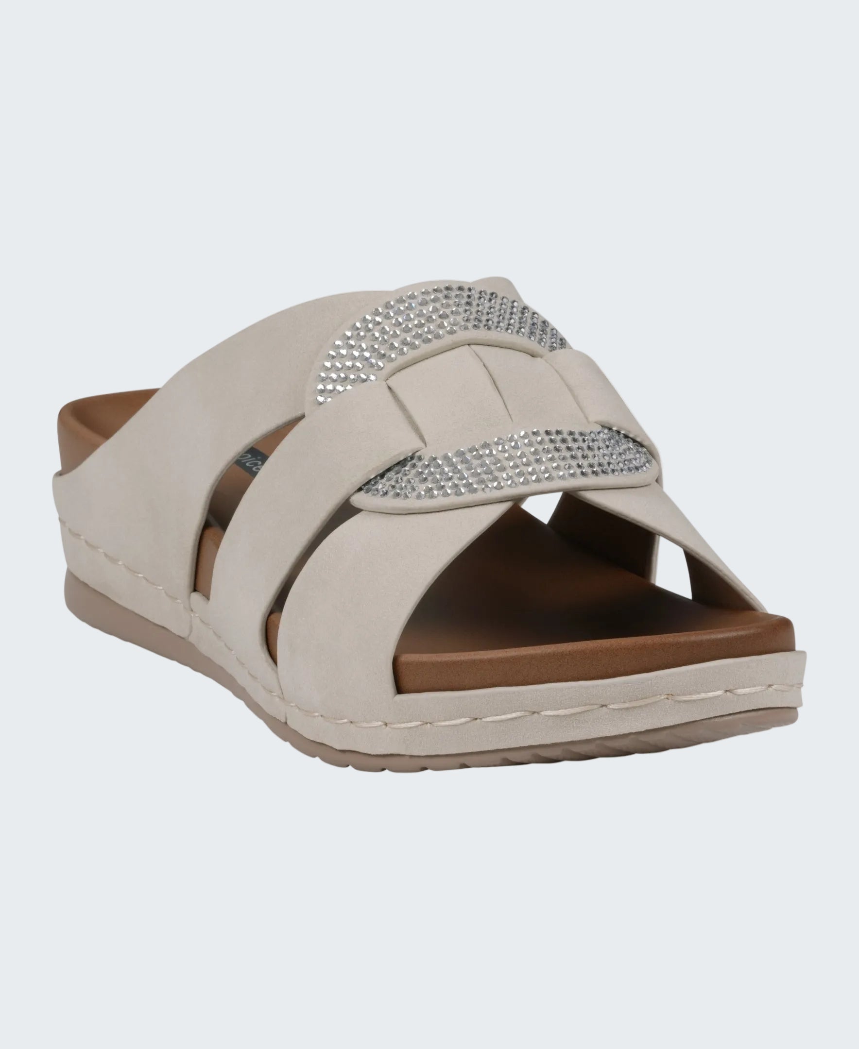 Beige sandal with a brown sole and silver embellishments on a white background