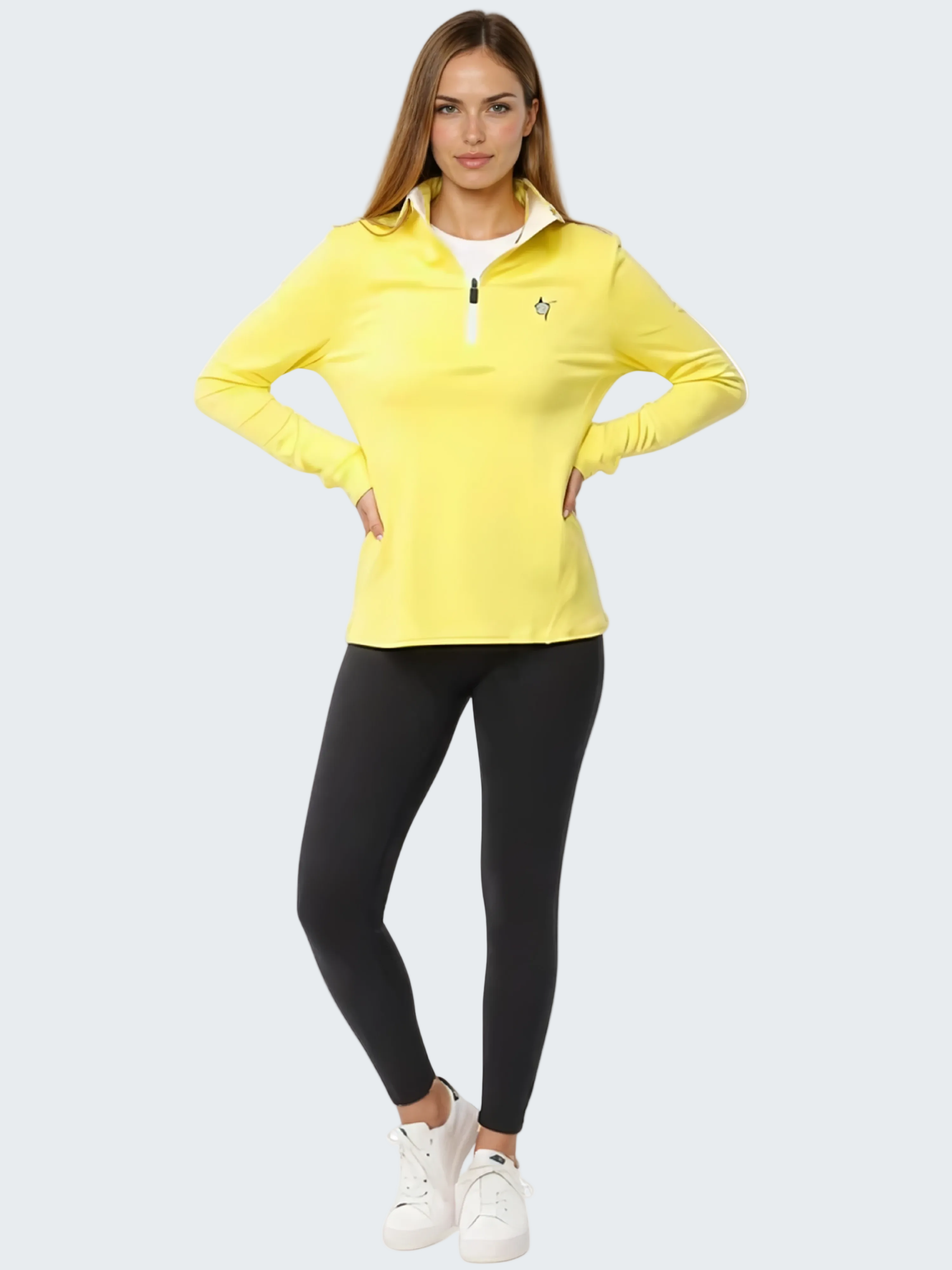Woman wearing a yellow long-sleeve top and black leggings on a white background