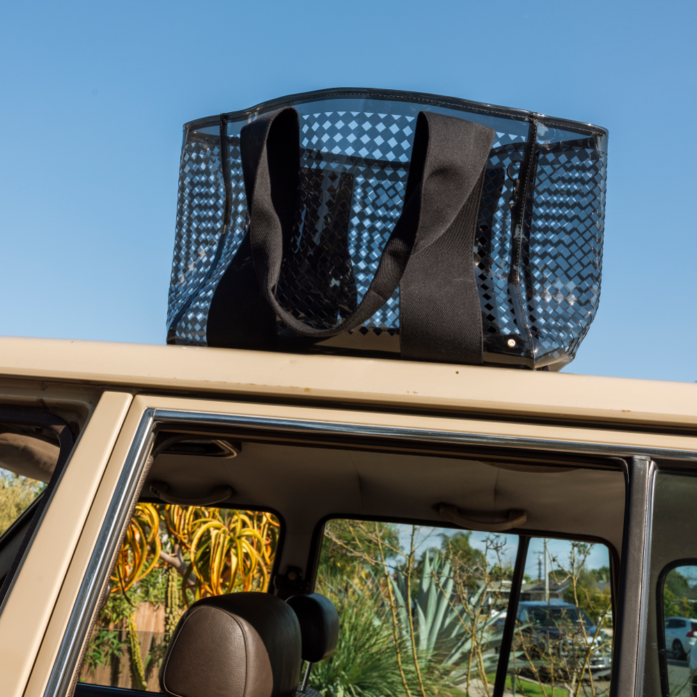 Black woven basket on a car roof with a clear blue sky background