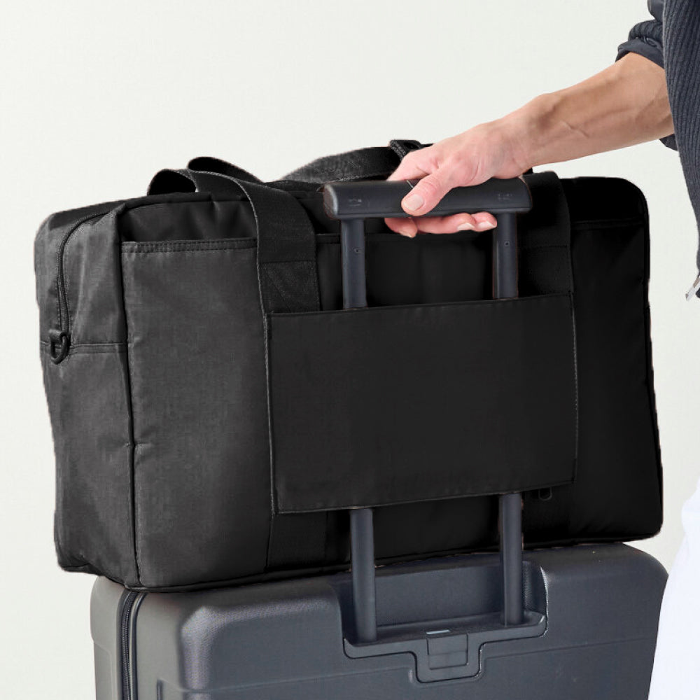 Black rolling duffel bag being held by a person with a white background
