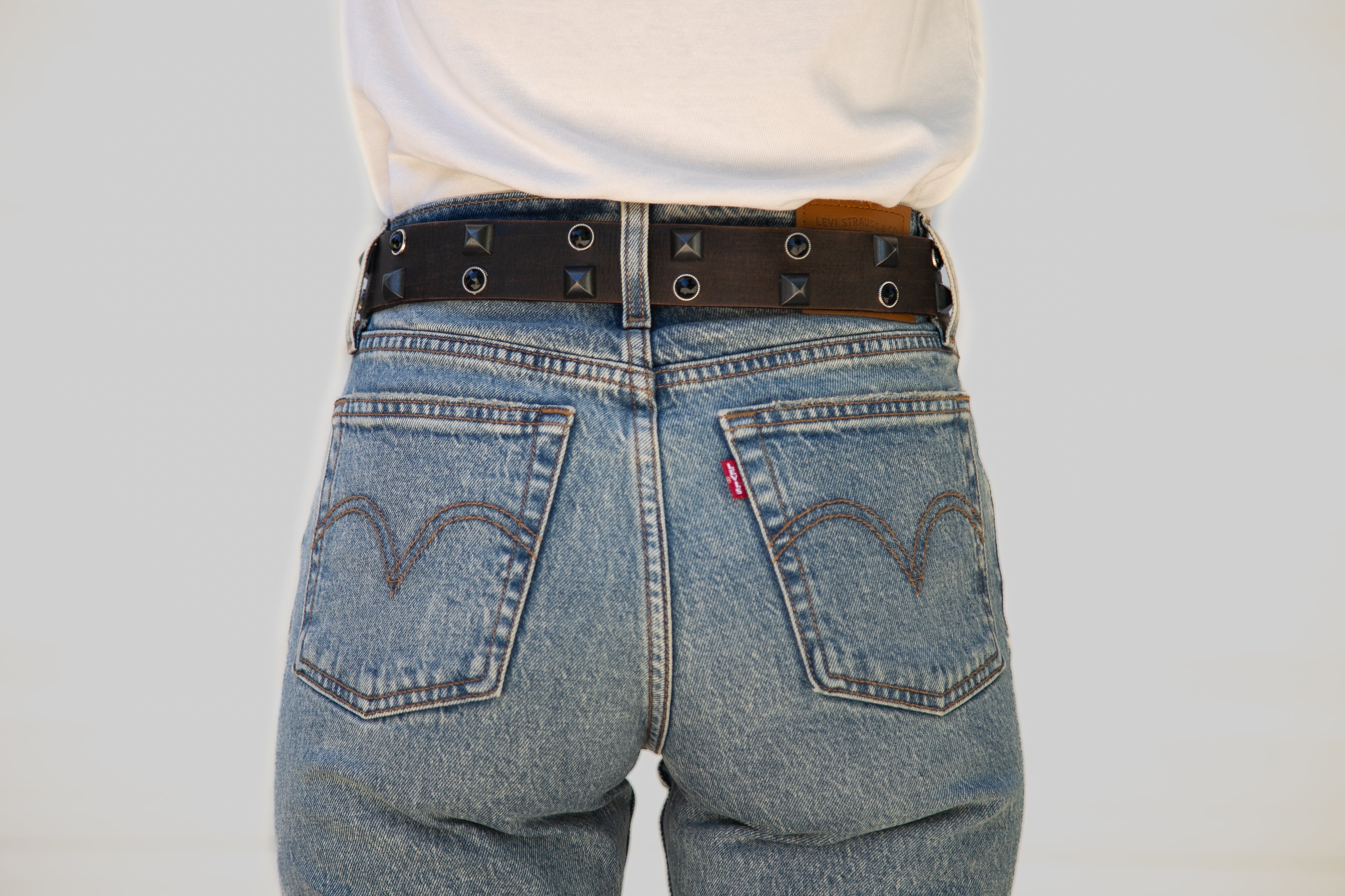 Person wearing blue jeans with a Levi's logo on a plain background