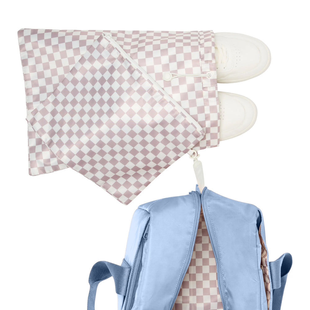 Pink checkered bag with white feet attached to a blue backpack on a white background