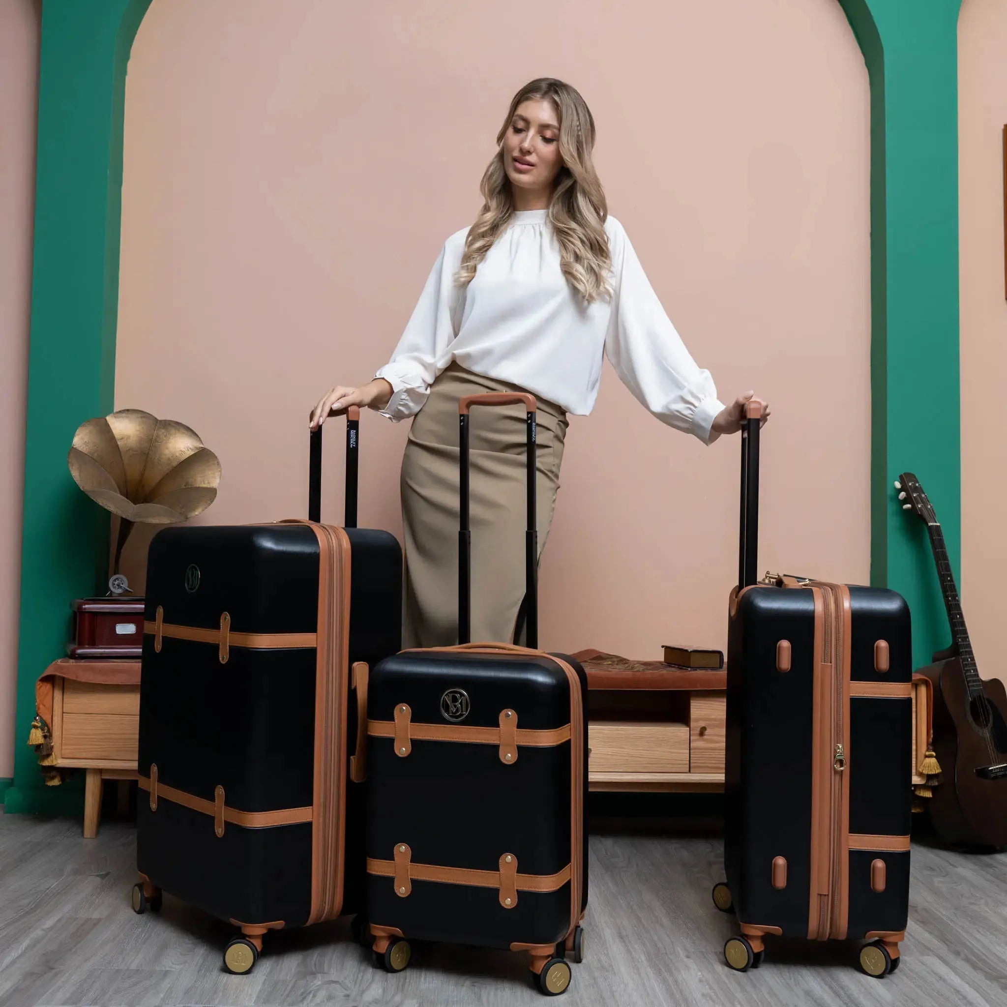 Woman standing with black suitcases with brown accents in a stylish interior setting