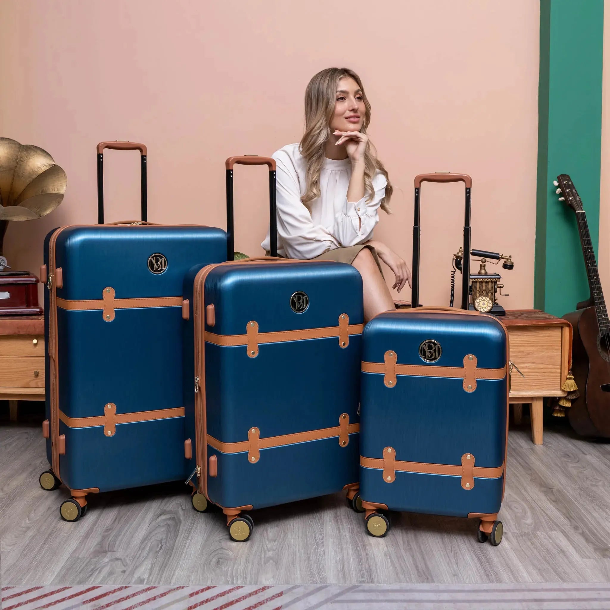 Woman sitting among blue suitcases with brown accents in a stylish room.