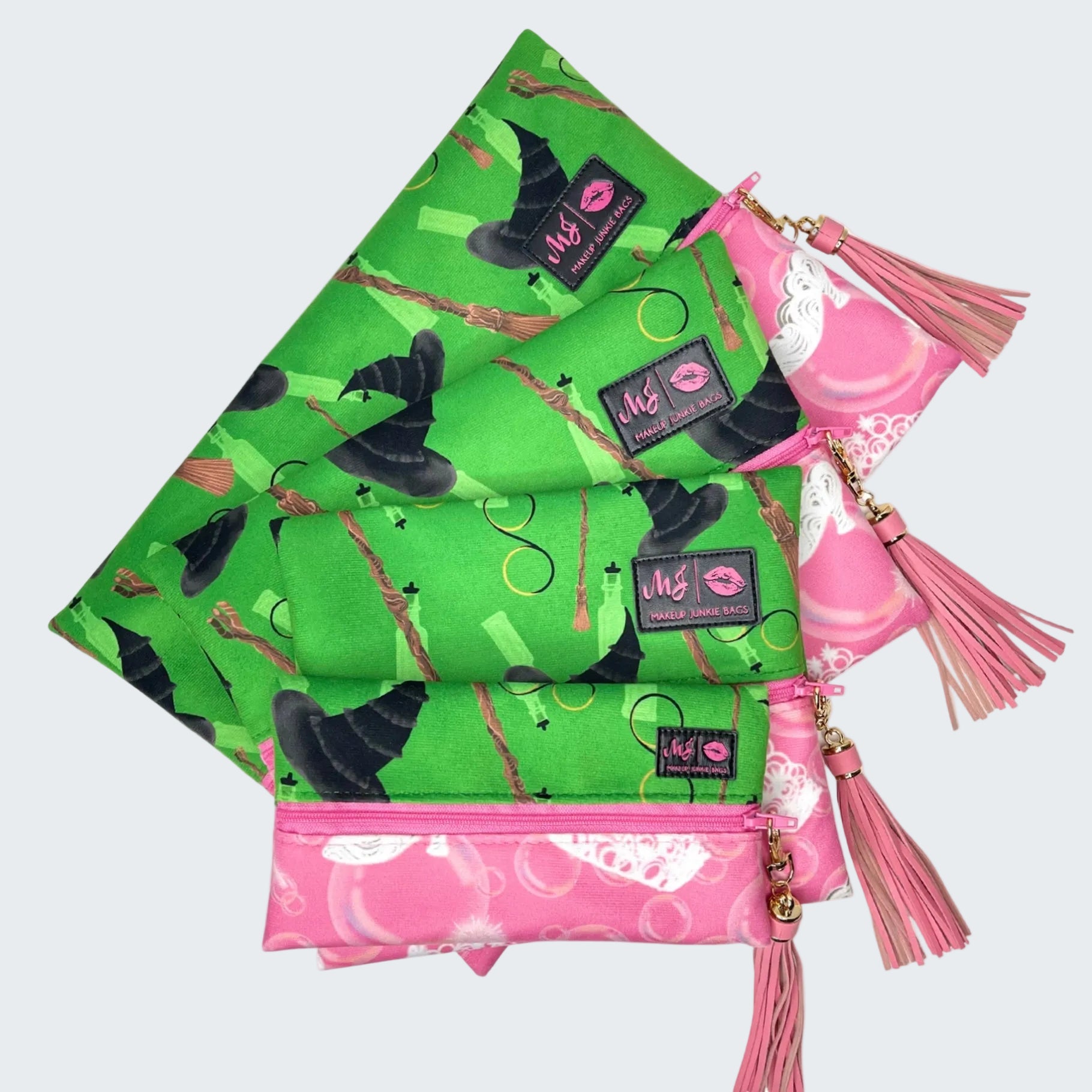 Two reusable bags, one green with witch-themed design and the other pink with tassels, on a white background.