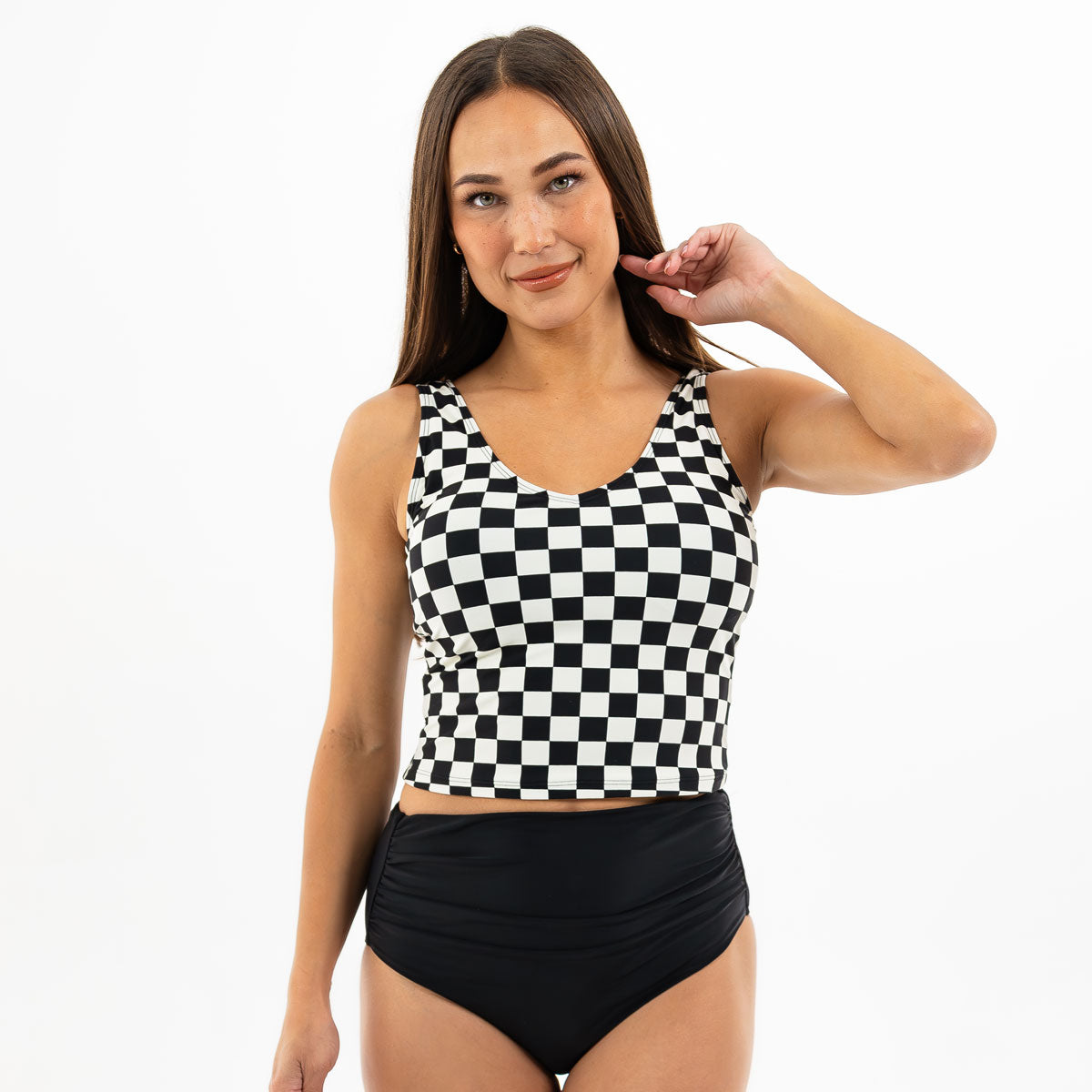 Woman wearing a black and white checkered top with a plain background