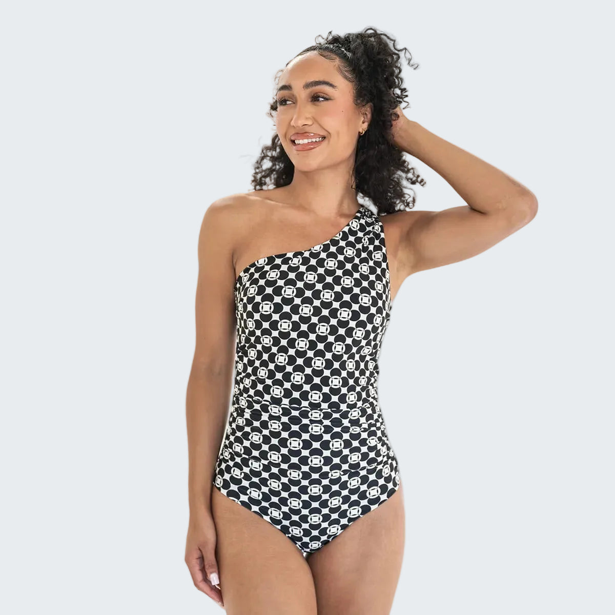 Woman wearing a black and white patterned one-piece swimsuit on a white background