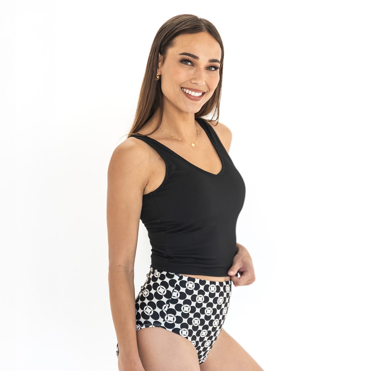 Woman wearing a black tank top and patterned shorts on a white background