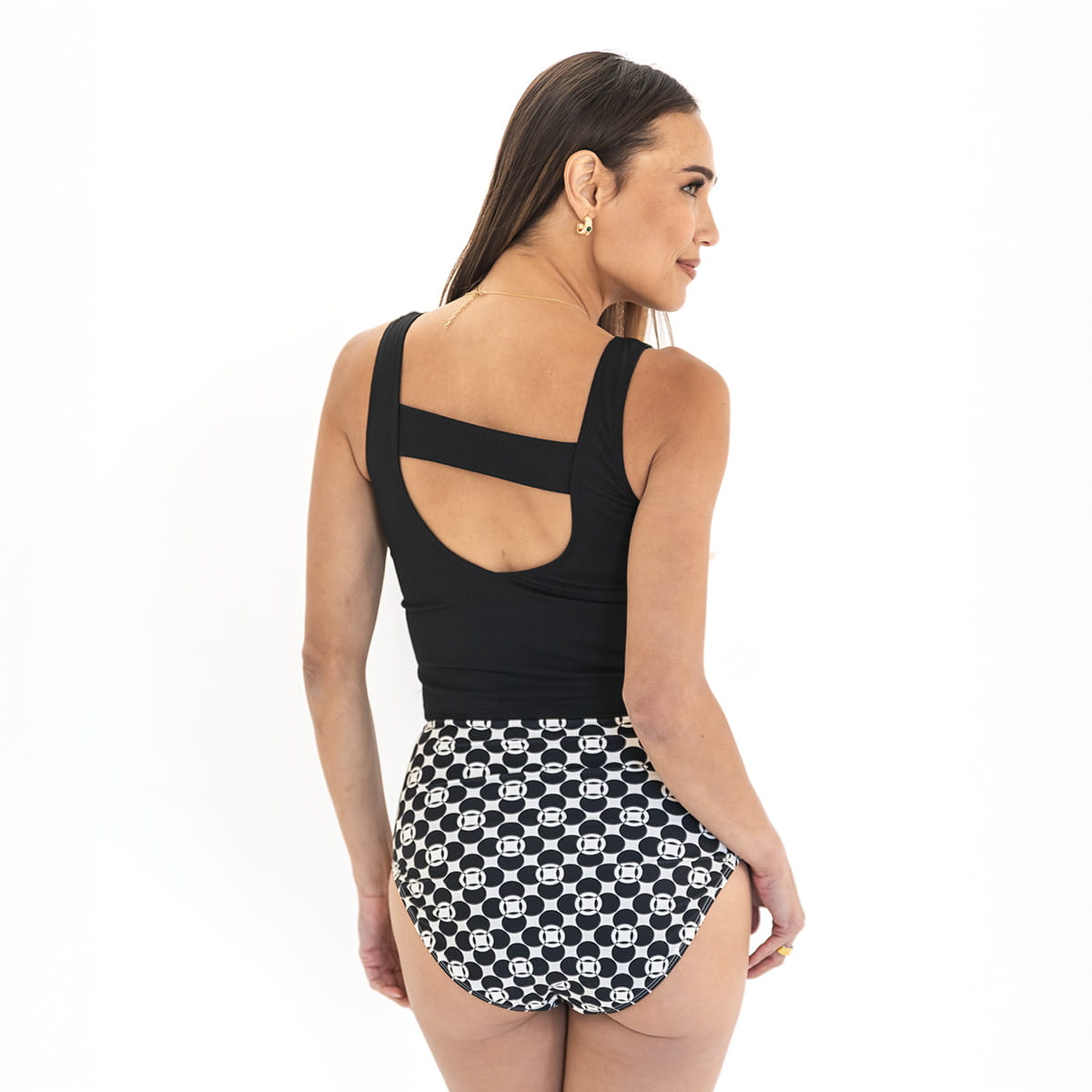Woman wearing a black tank top and patterned shorts on a white background