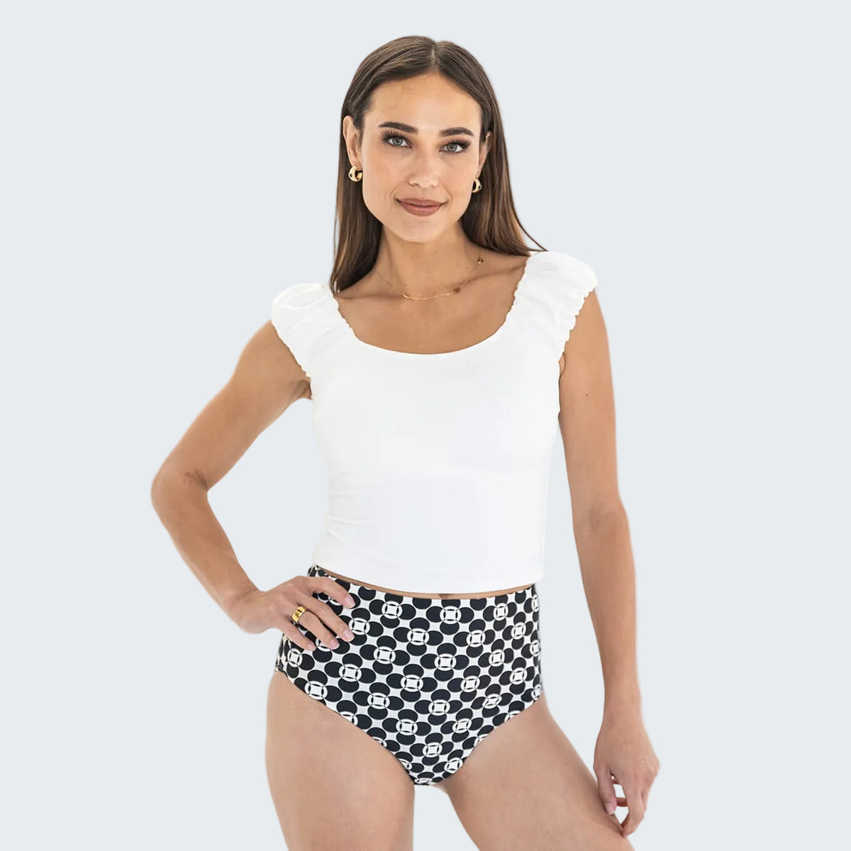 Woman wearing a white top and black and white patterned shorts on a white background