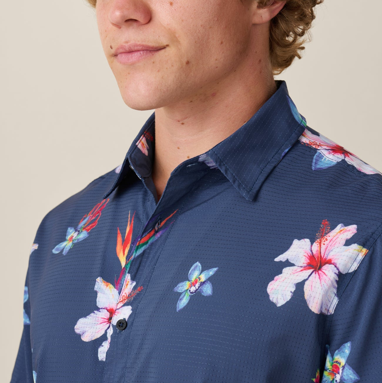 Man wearing a navy blue floral-patterned shirt against a neutral background