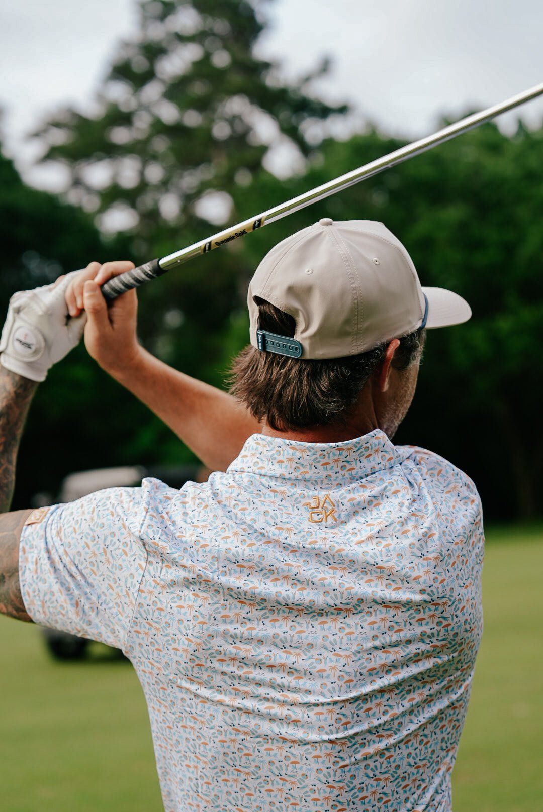 Person playing golf on a green course with trees in the background