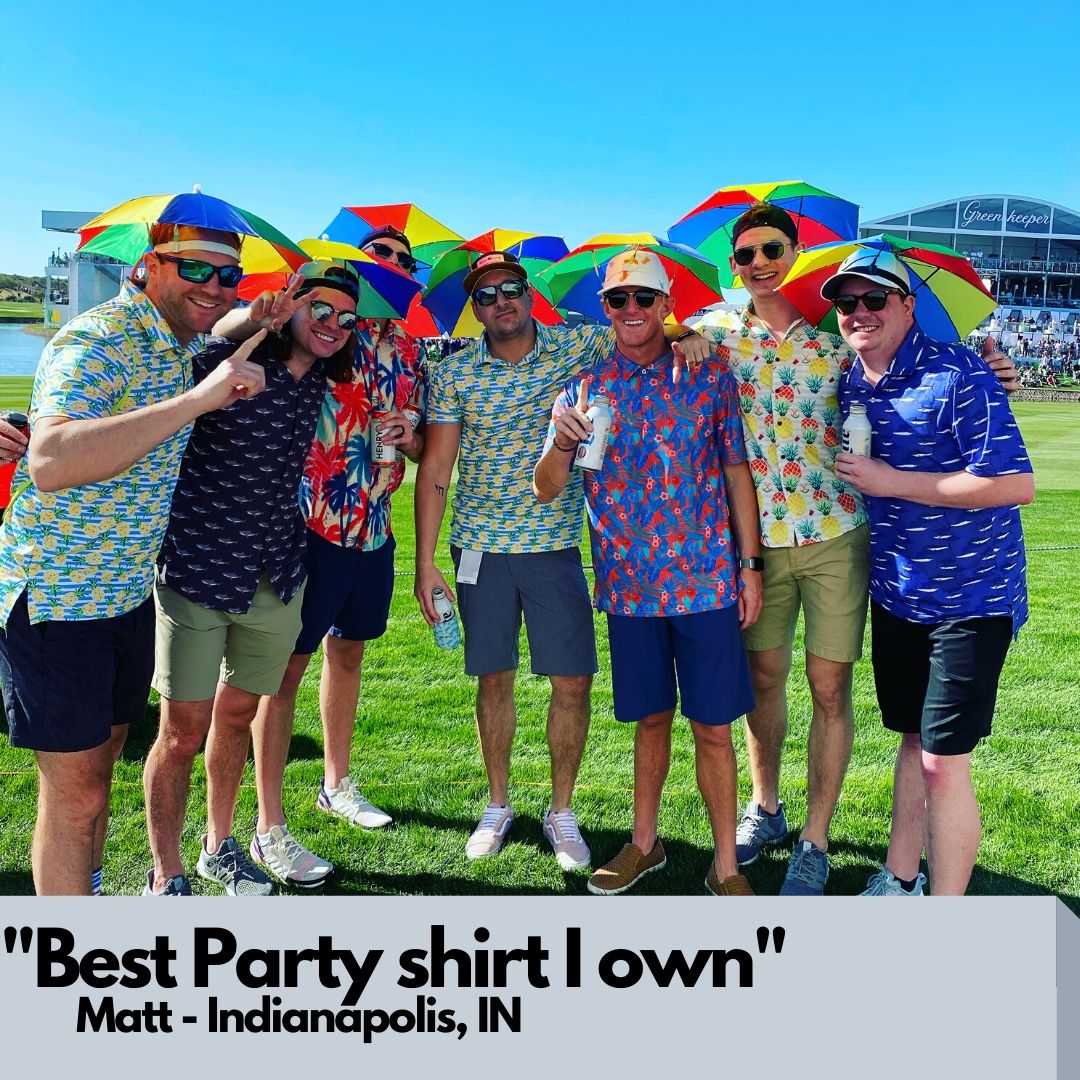 Group of people posing together with colorful shirts and umbrellas on a grassy field.