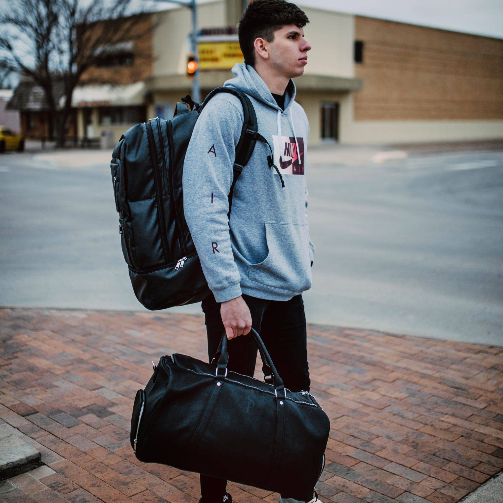 Person with a backpack and duffel bag on a city street