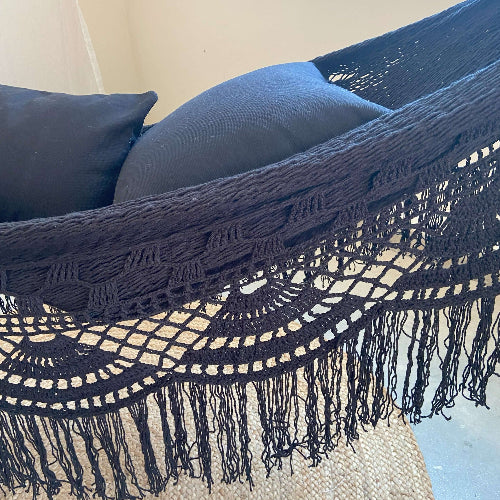 Navy blue macrame throw blanket with fringe on a surface