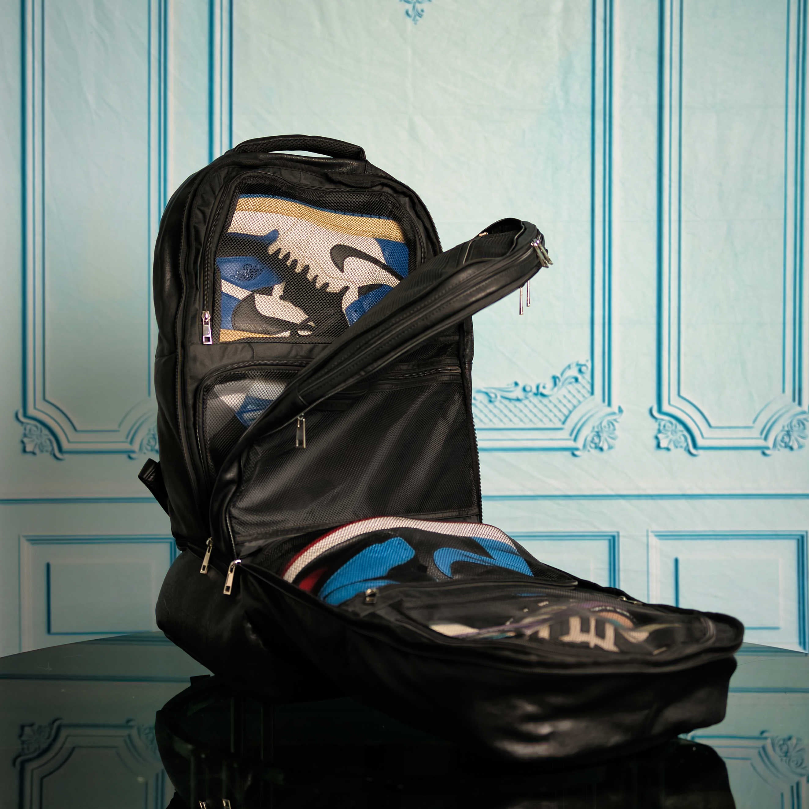 Black backpack with colorful items inside against a decorative wall.