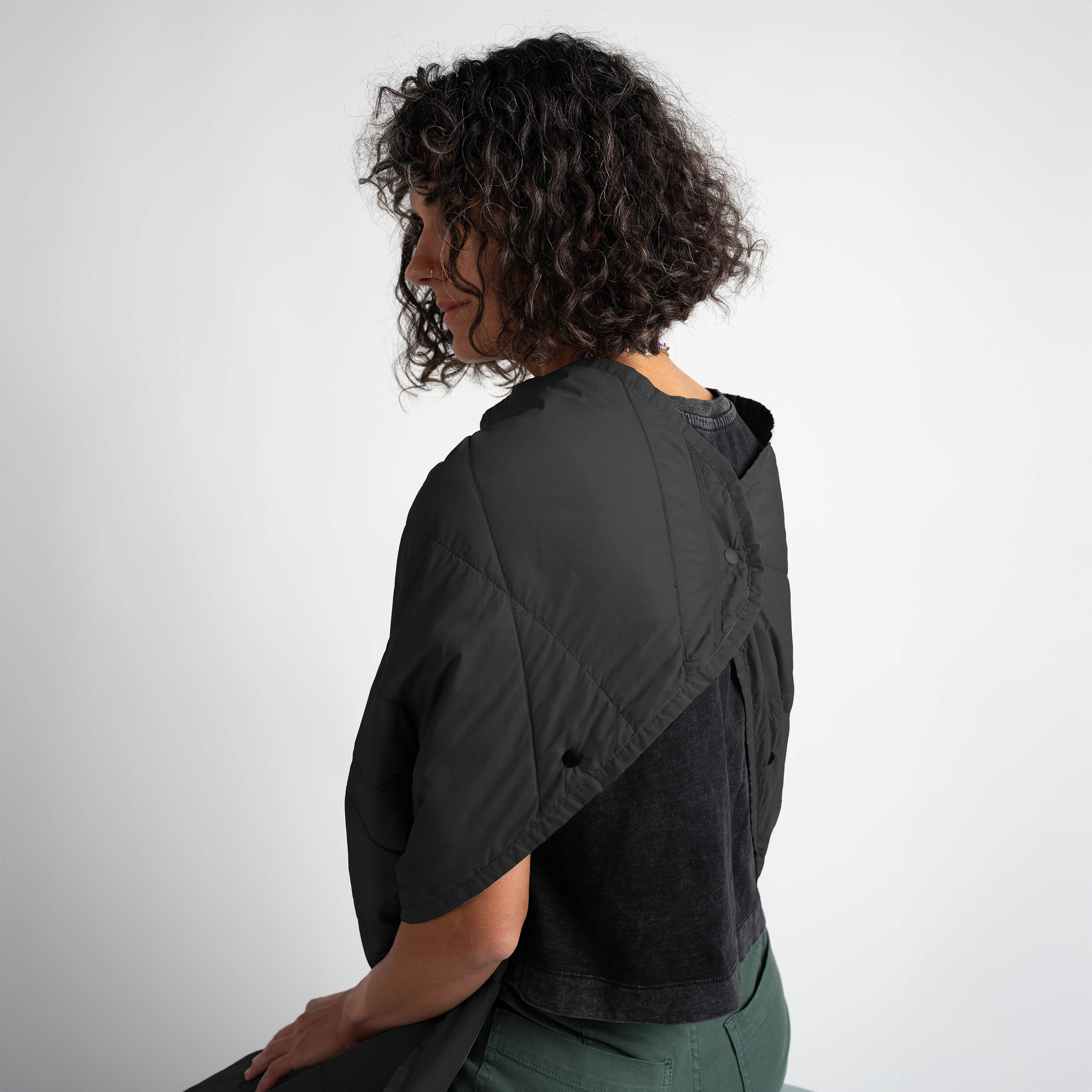 Person wearing a black quilted jacket with a plain background