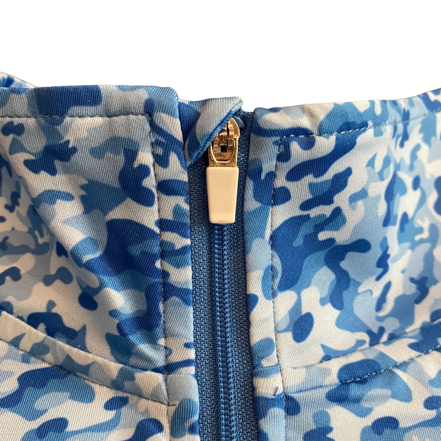 Blue camouflage-patterned fabric with a gold zipper on a white background