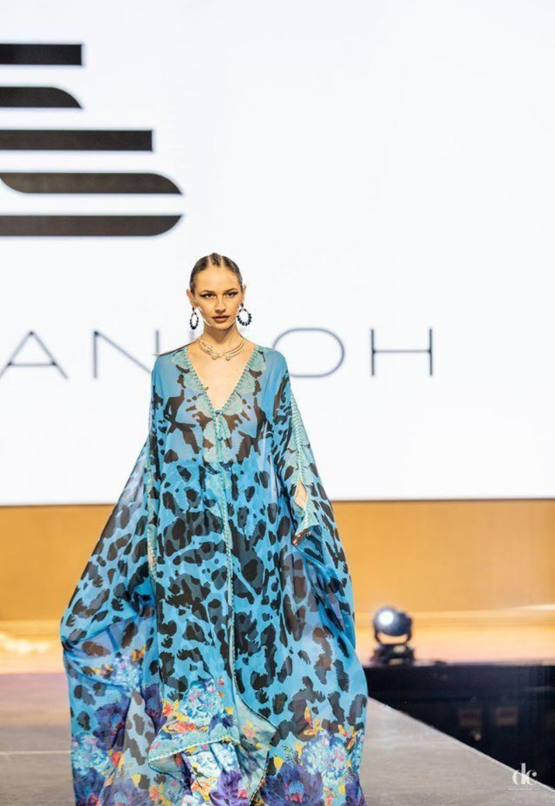 Model wearing a blue floral dress on a runway with 'Chanel' branding.