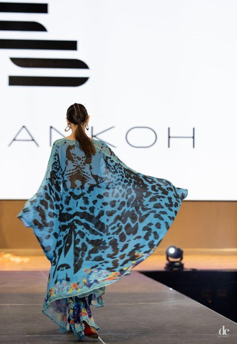 Model wearing a blue leopard print dress on a runway with 'LANKOH' branding.