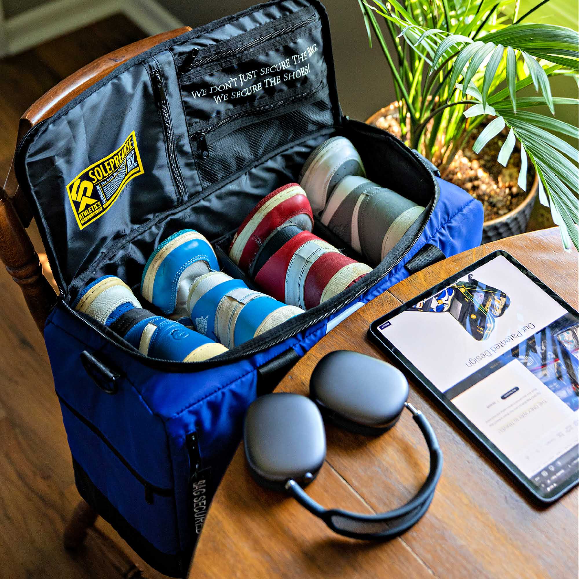 Blue bag with security devices, a phone, and a plant on a wooden surface.