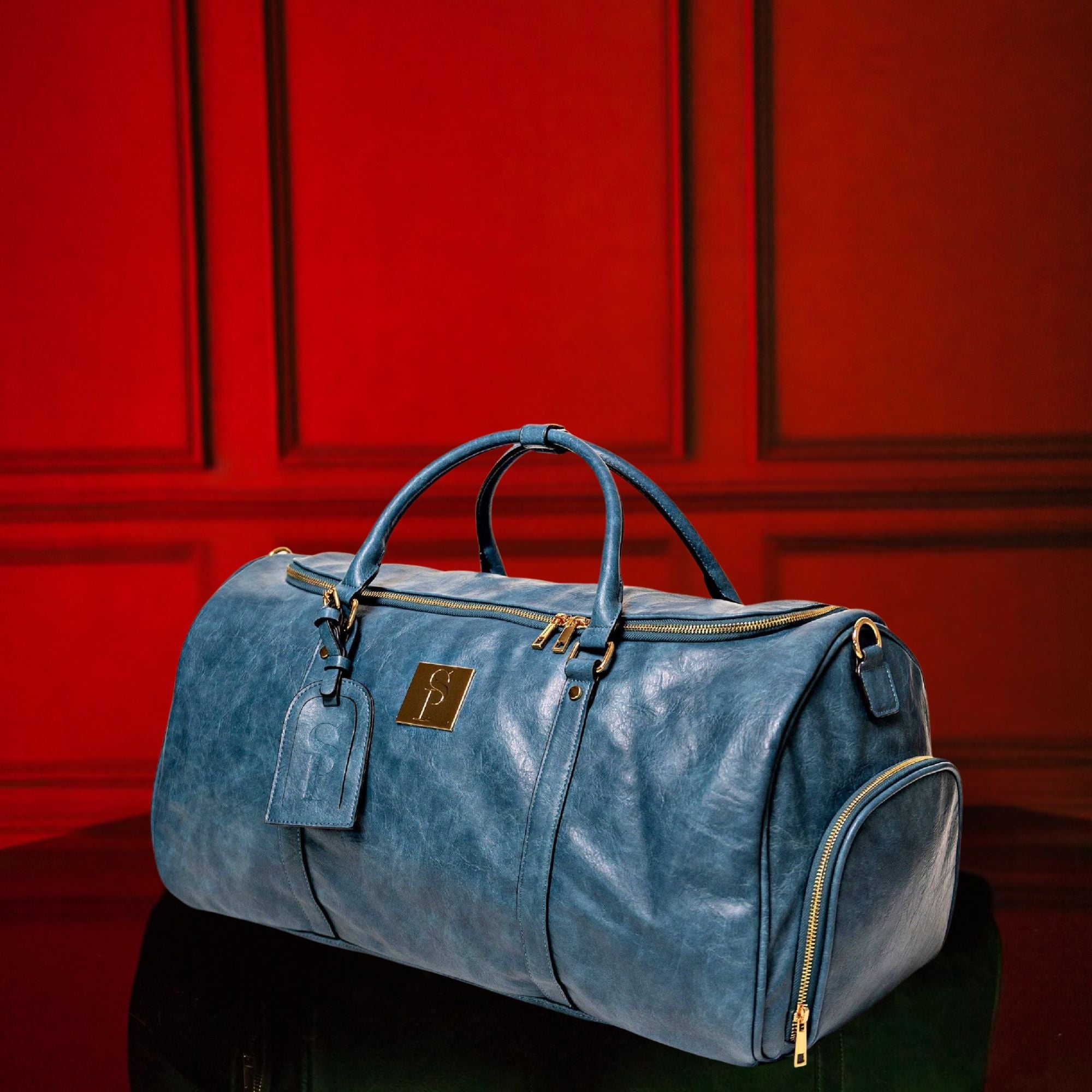 Blue duffel bag with gold zippers on a red paneled background