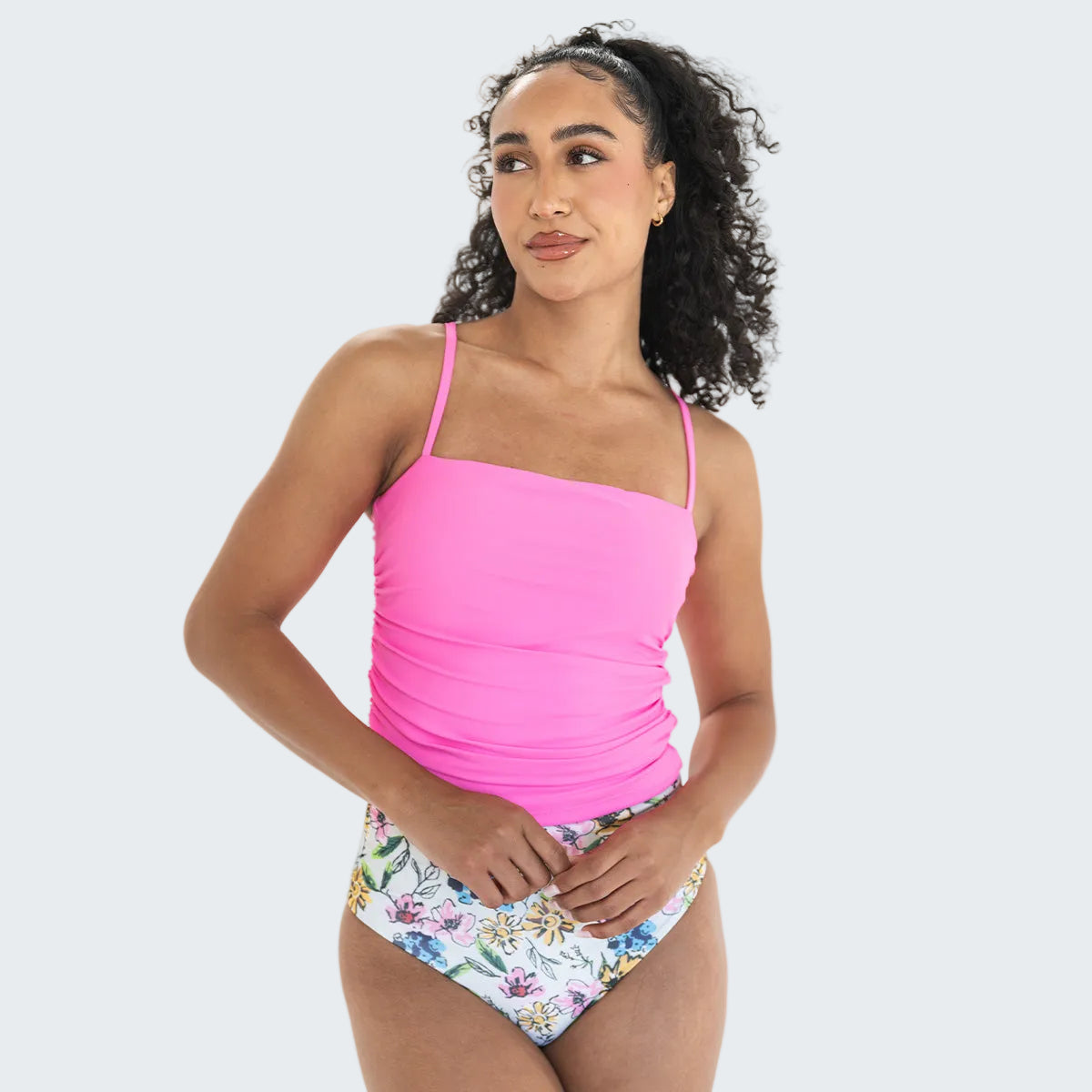 Woman wearing a pink tankini top and floral bottom on a white background