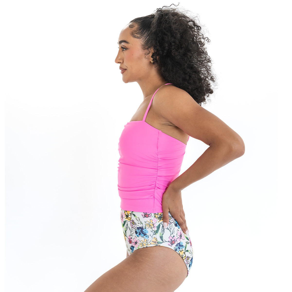 Woman wearing a pink top and floral shorts on a white background