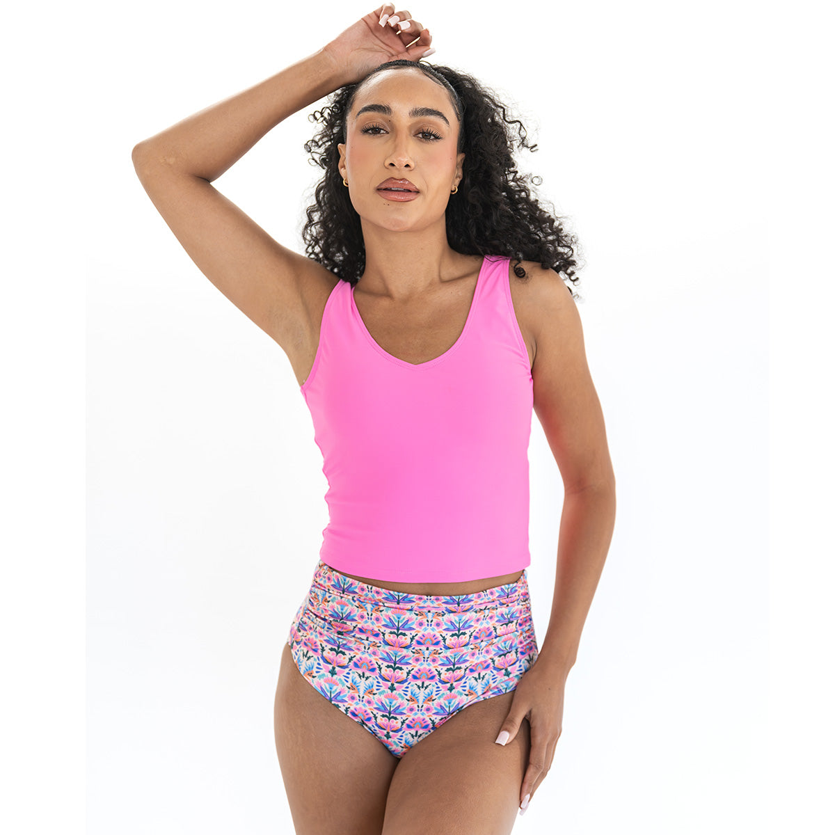 Woman wearing a pink tank top and patterned high-waisted bikini bottom on a white background