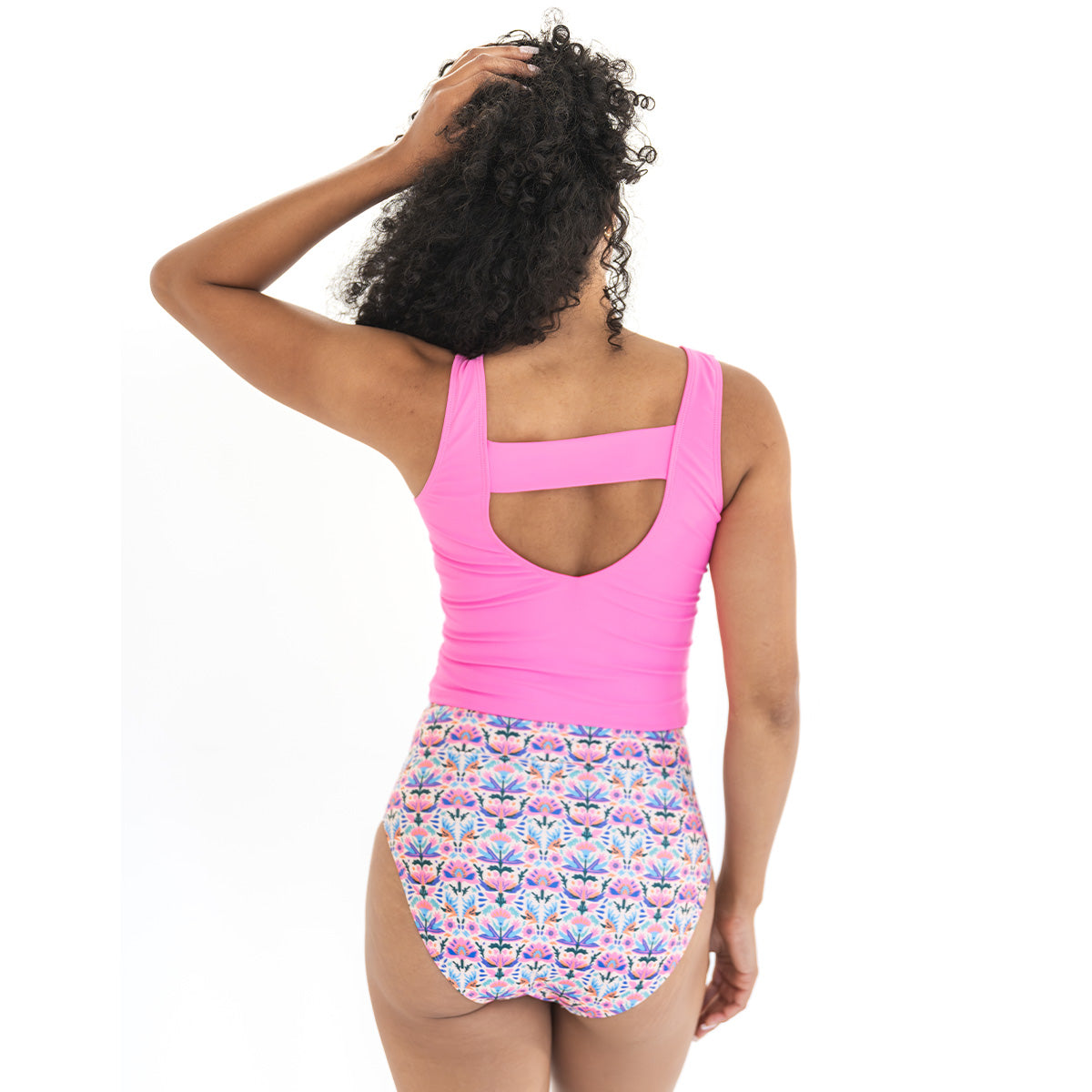 Woman wearing a pink tank top and floral skirt on a white background