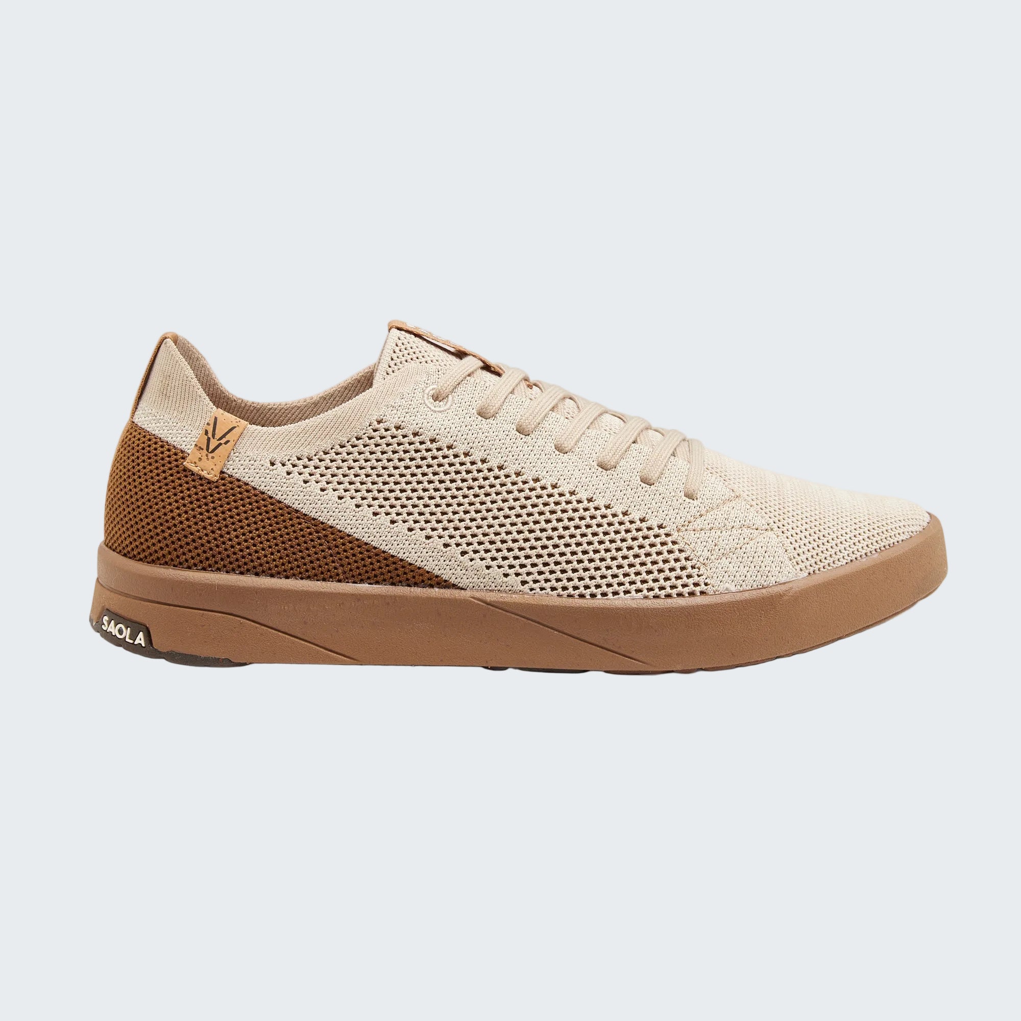 A low-top knit sneaker in beige and brown, featuring a beige knit upper with a brown mesh panel on the side, a brown midsole, and a small tan leather logo tab on the heel.