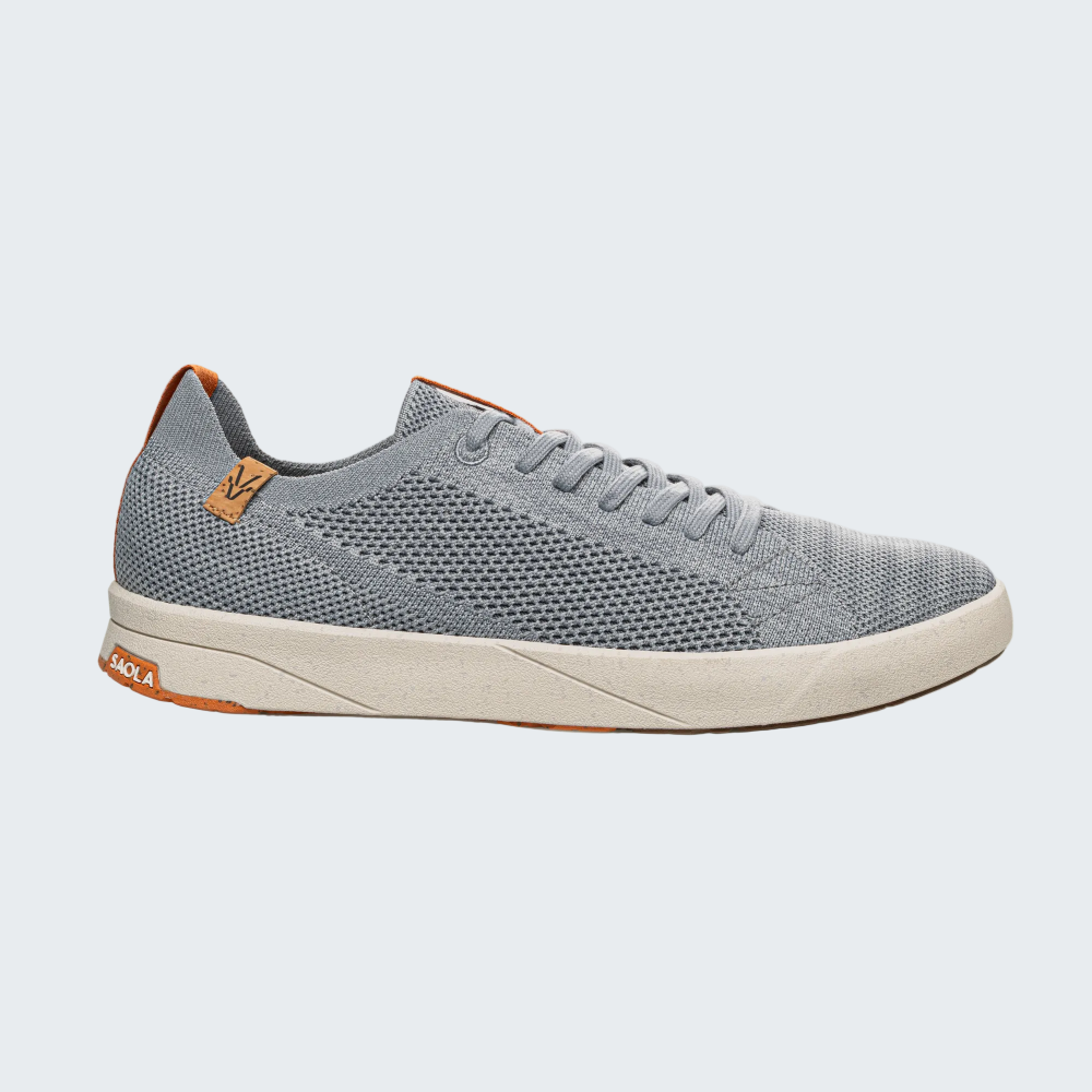 A light gray knit sneaker with a cream-colored midsole and small orange-brown accents on the heel and tongue, shown from a side profile on a light gray background.