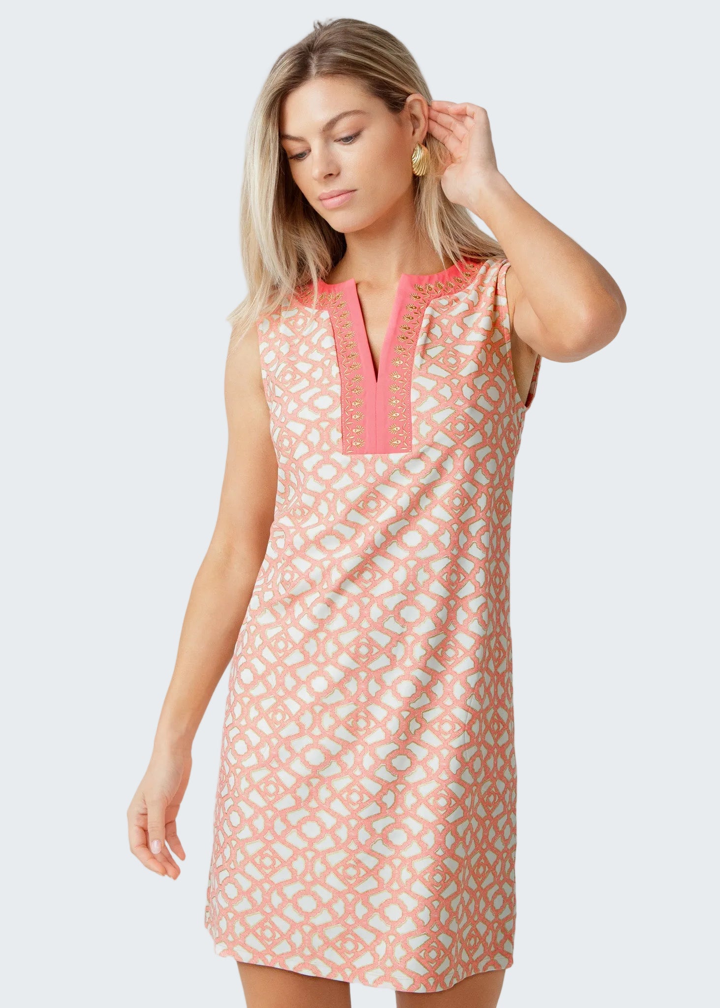 Woman wearing a sleeveless dress with pink geometric pattern on a white background