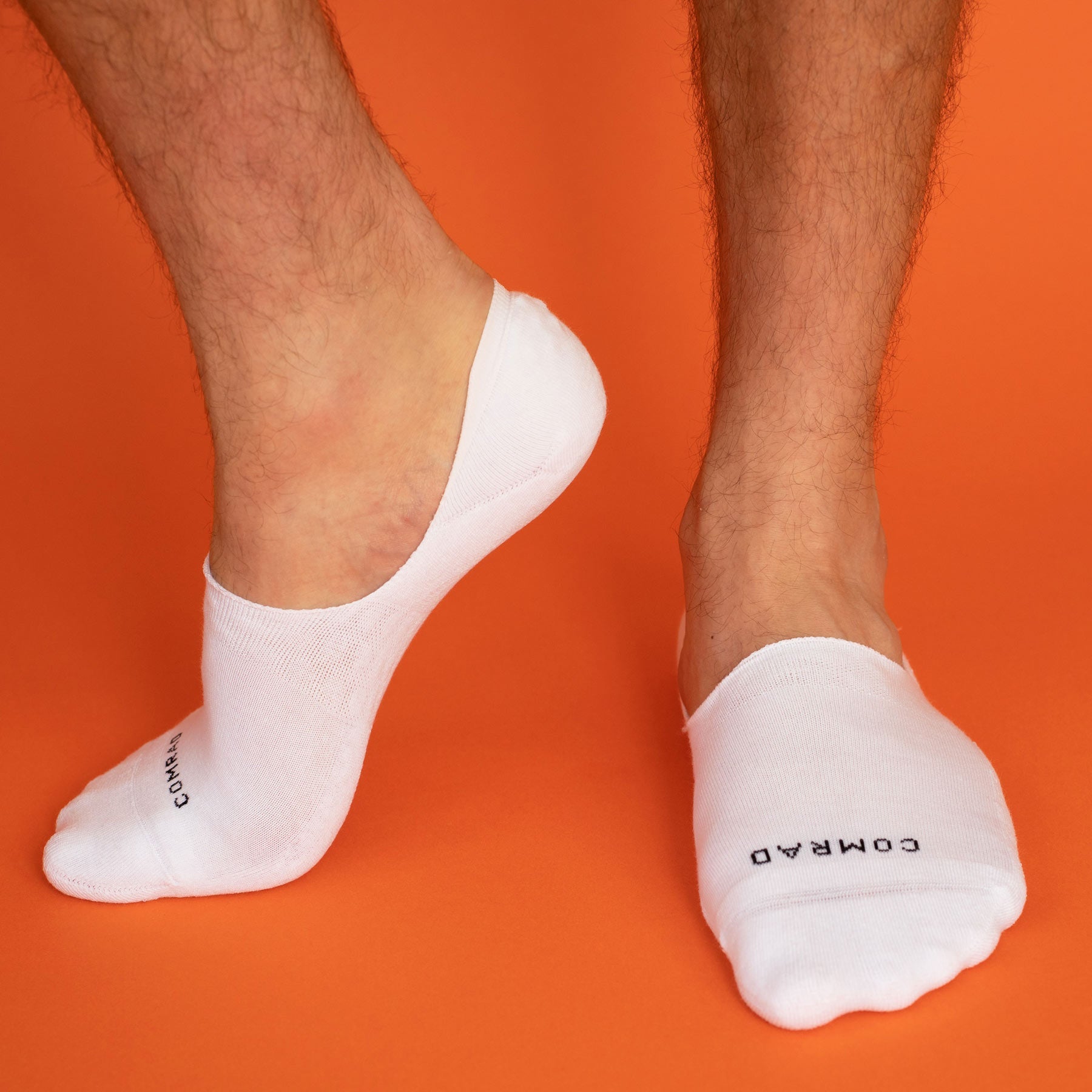 White no-show socks worn on orange background