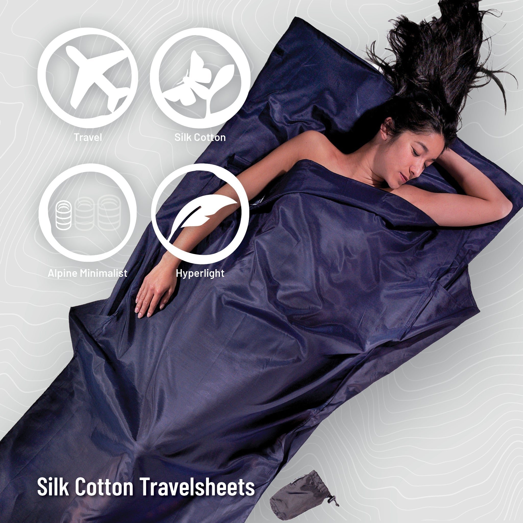 Person lying in a dark blue silk cotton travelsheet with product features highlighted.