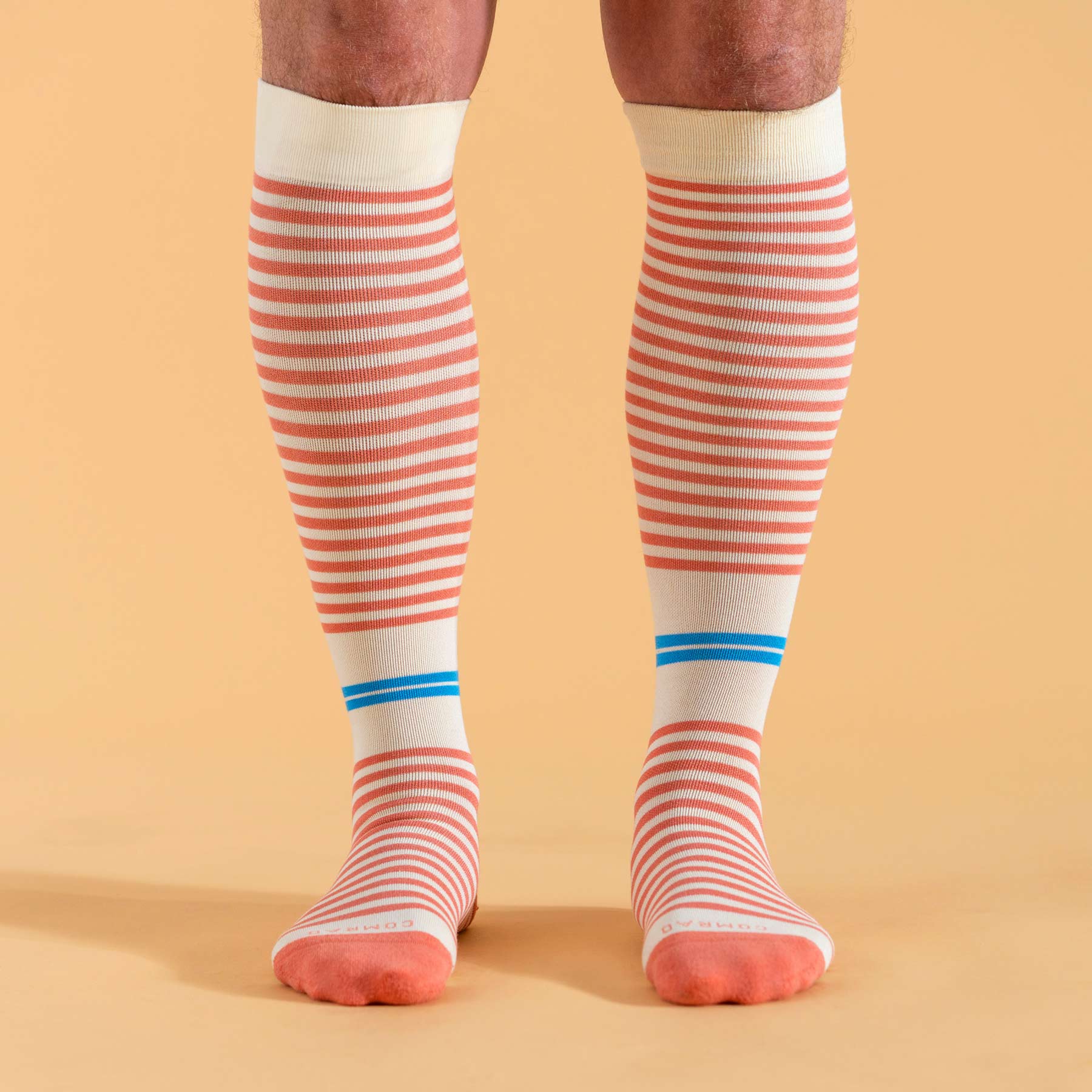 Knee-high socks with red and white stripes and blue accents on a beige background