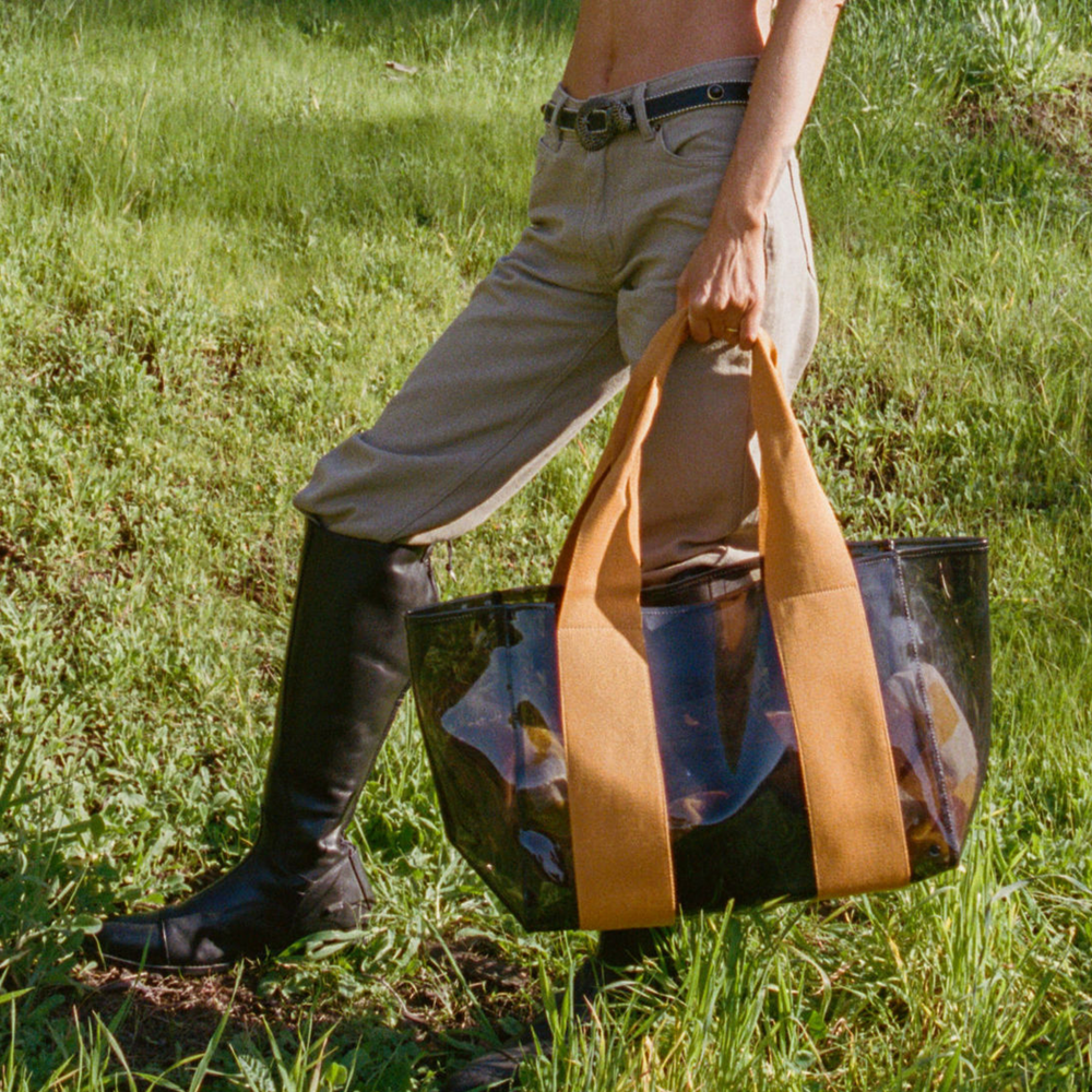 Person walking outdoors holding a large tote bag with a scenic design.